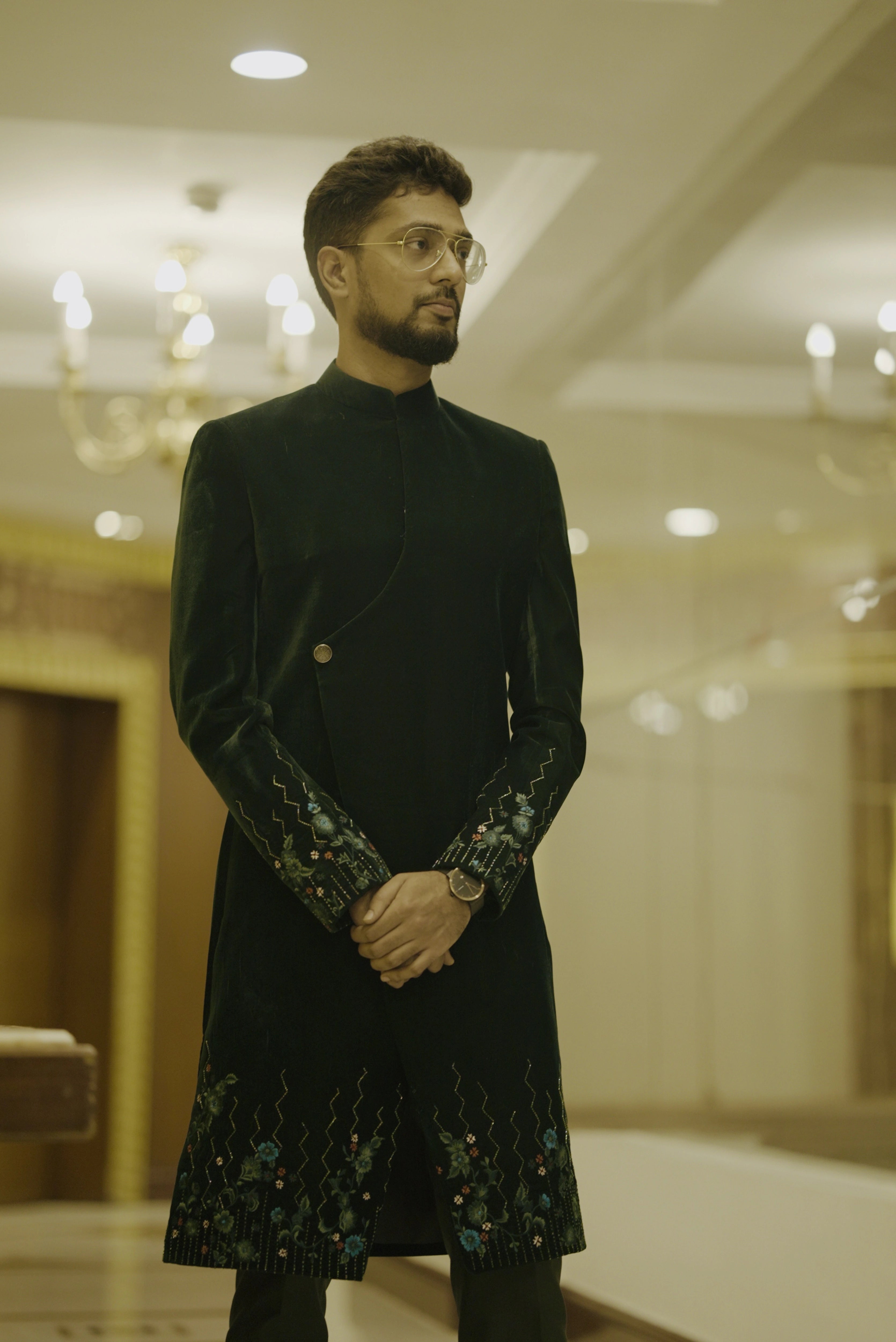 Groomsman Mahesh from Bangalore posing in a bottle green velvet sherwani handcrafted by team Archana Karthick.