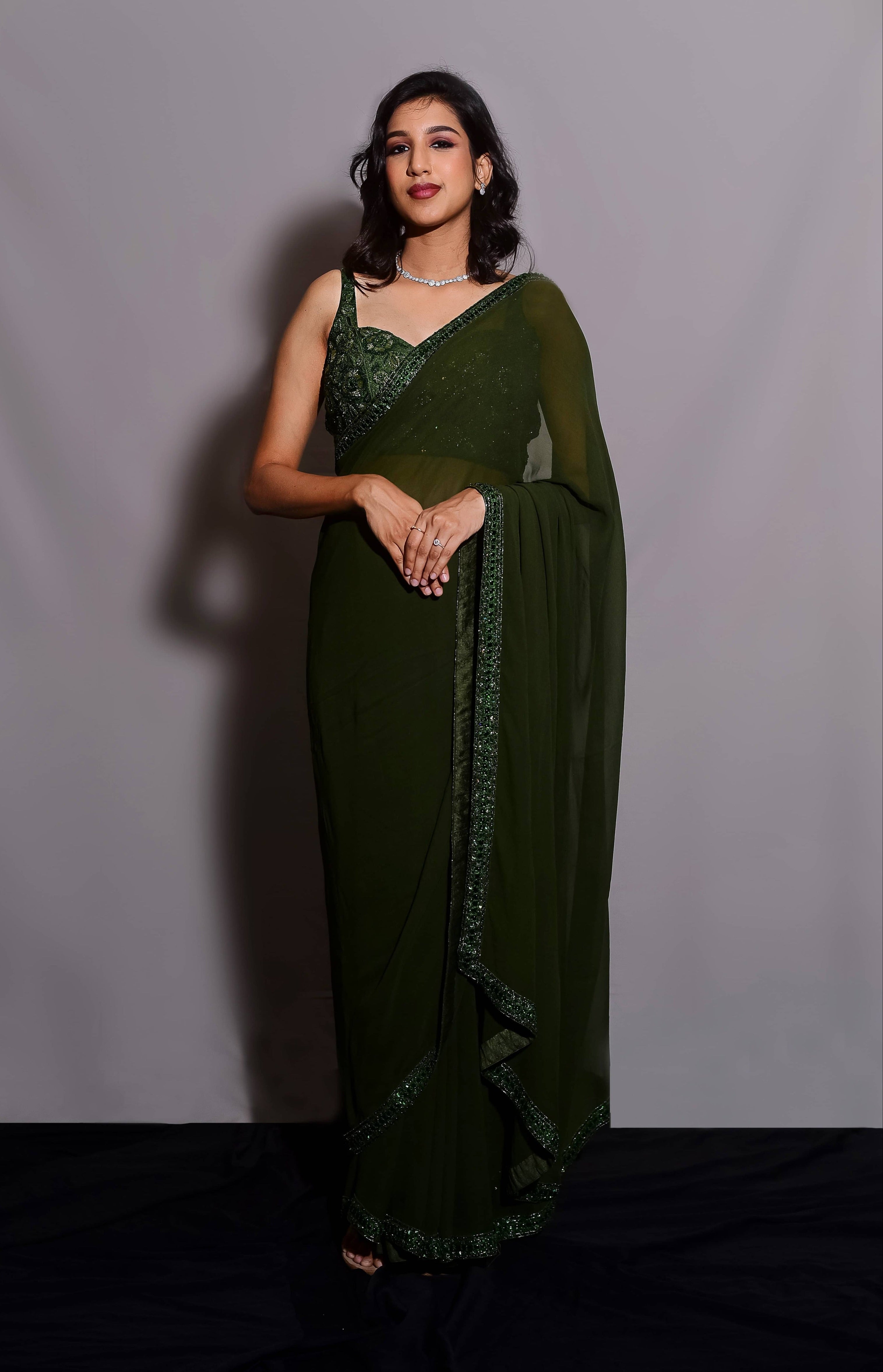 Influencer & Model Ashwini Kumar posing in a moss Green georgette saree paired with a heavily embellished bralette from the Lo-Mance Collection by Archana Karthick.
