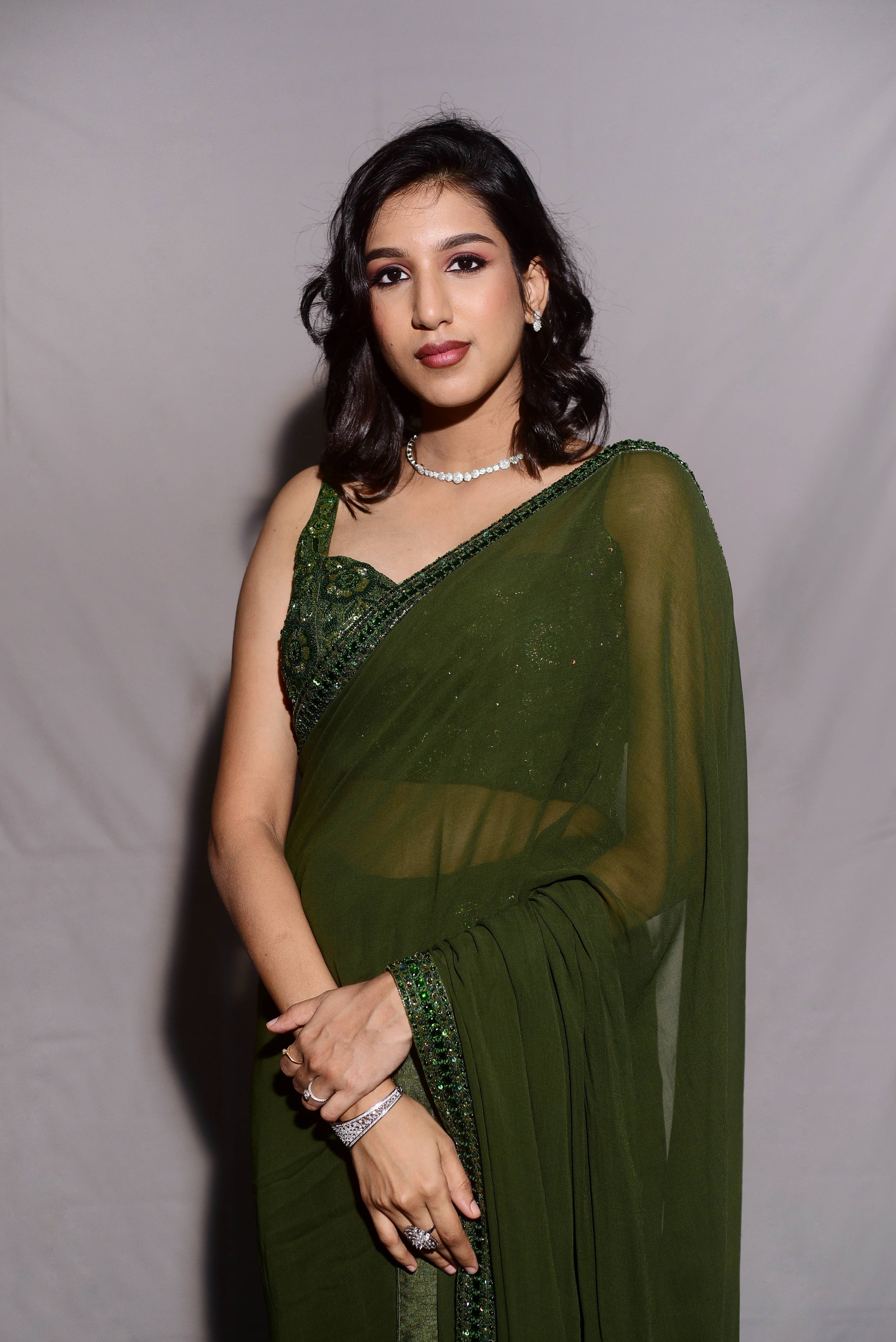 Influencer & Model Ashwini Kumar in a photoshoot in a moss Green georgette saree paired with a heavily embellished bralette from the Lo-Mance Collection by Archana Karthick.