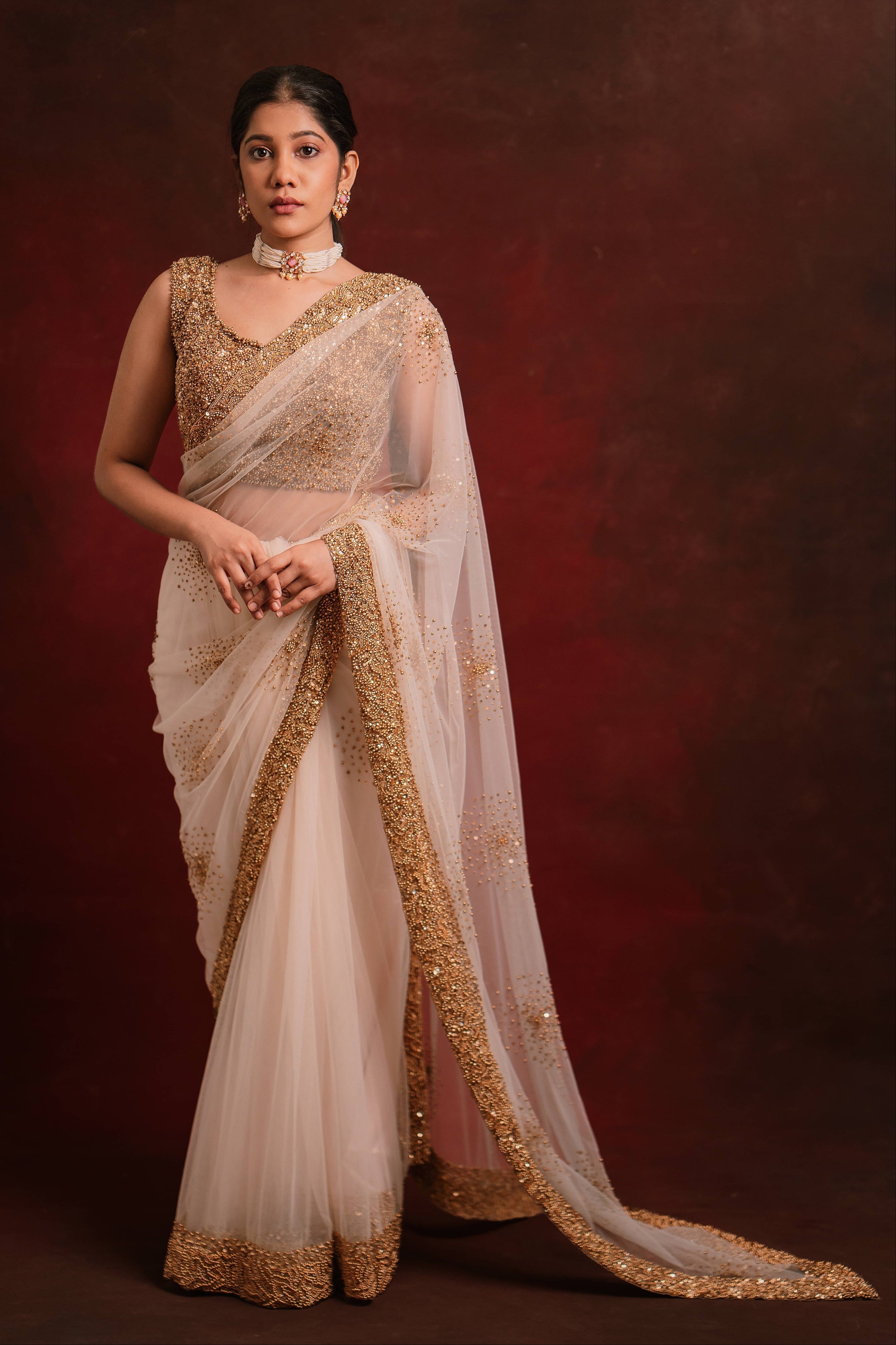 Ivory tulle saree intricately handcrafted with antique gold beads and sequins paired with a handcrafted blouse featuring similar work by team Archana Karthick