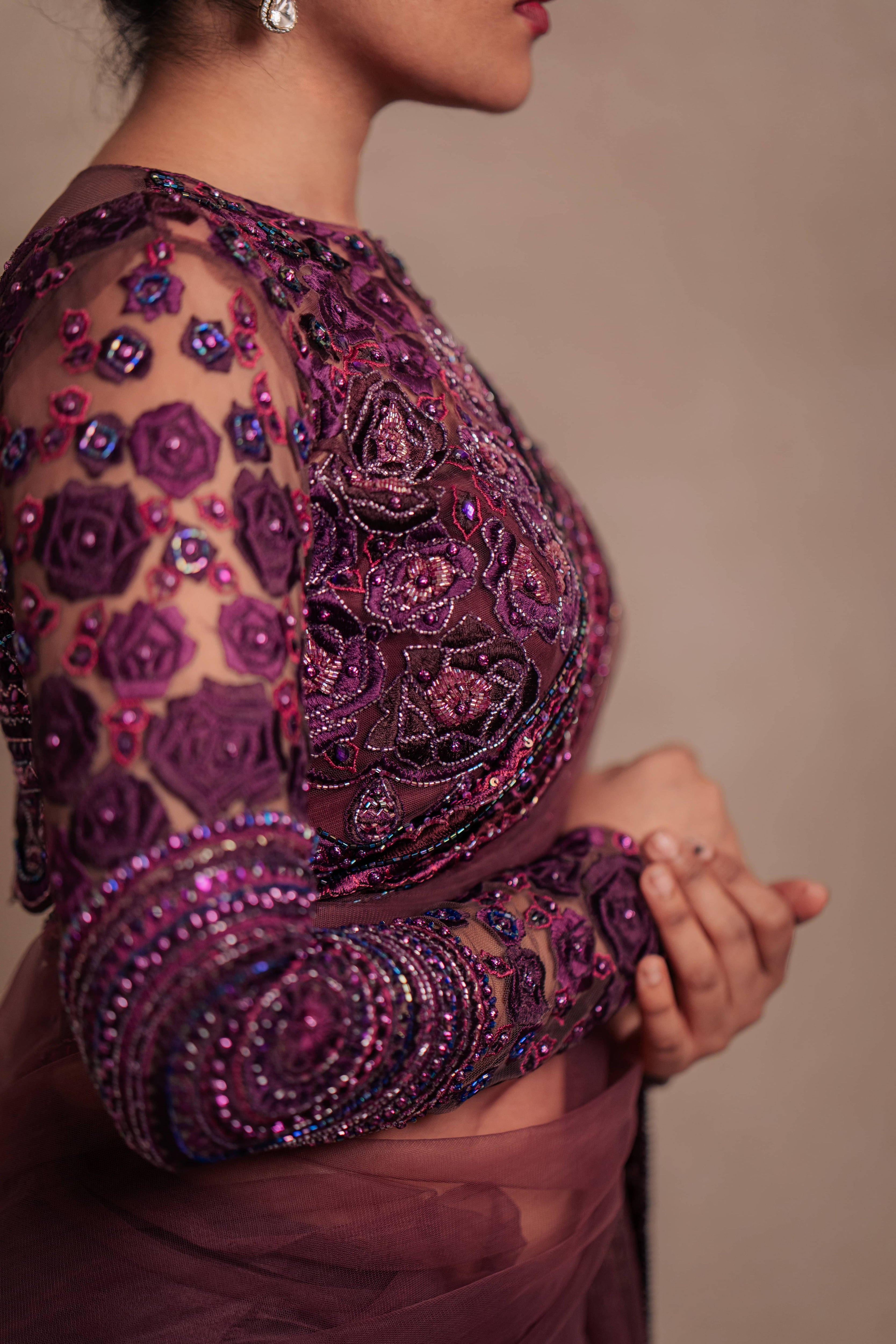 Jaina Parmar, known for recreating looks of actress Nayanthara is seen here in a purple net saree with heavily embellished border and full sleeved blouse with stone and resham work posing for closeup of blouse sleeve and cup design
