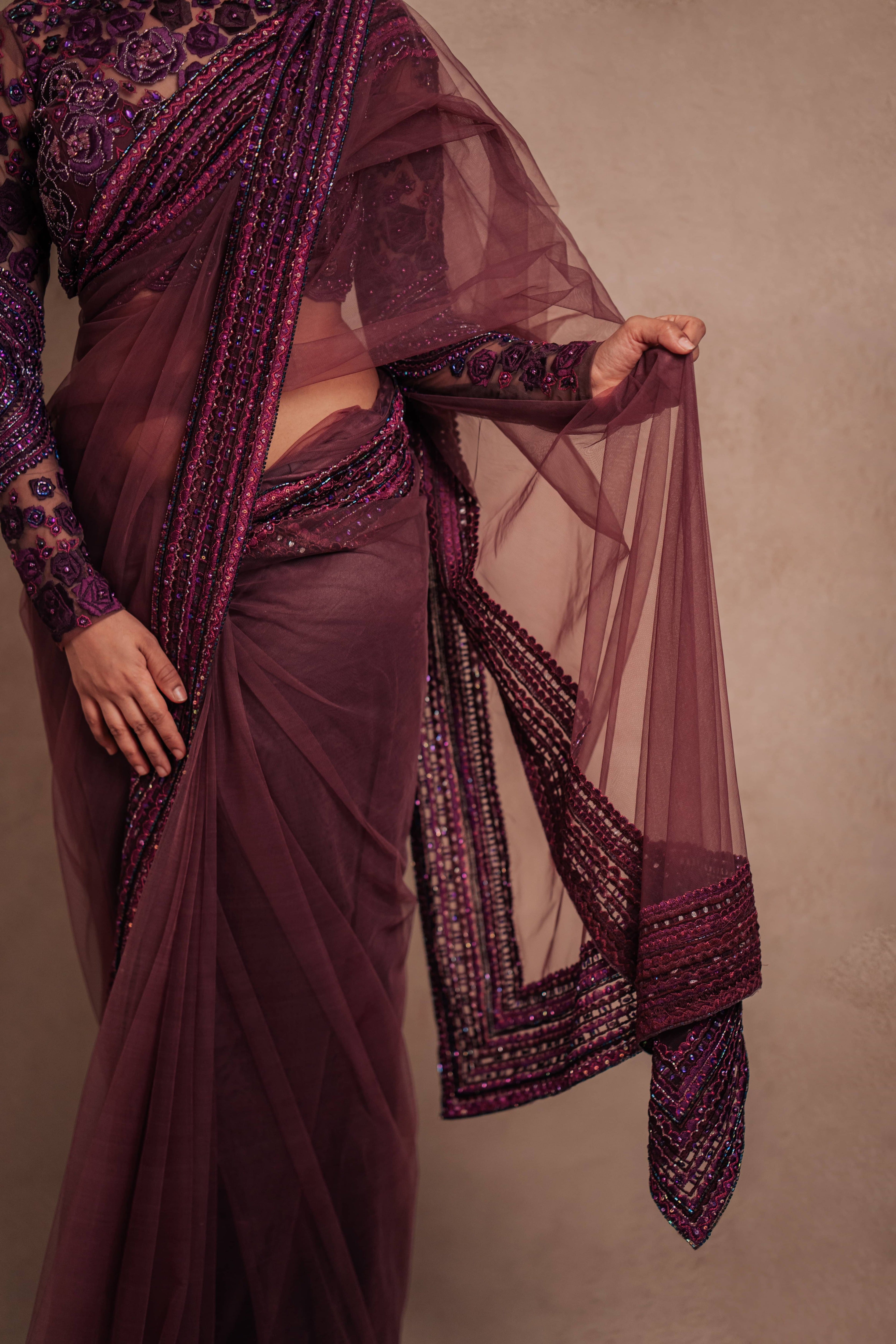 Jaina Parmar, known for recreating looks of actress Nayanthara is seen here in a purple net saree with heavily embellished border and full sleeved blouse with stone and resham work posing for closeup of front saree border