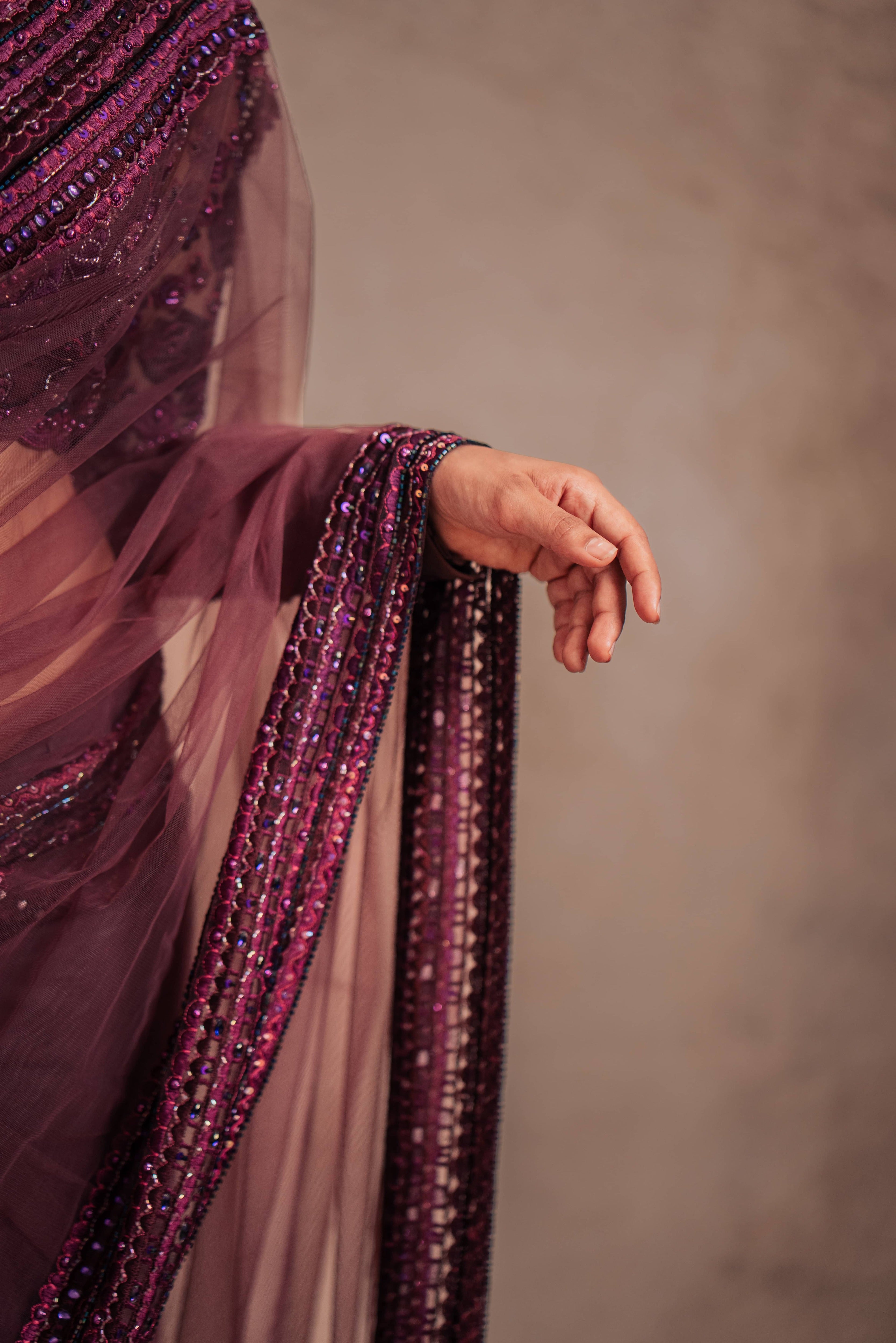 Jaina Parmar, known for recreating looks of actress Nayanthara is seen here in a purple net saree with heavily embellished border and full sleeved blouse with stone and resham work posing for closeup of saree border
