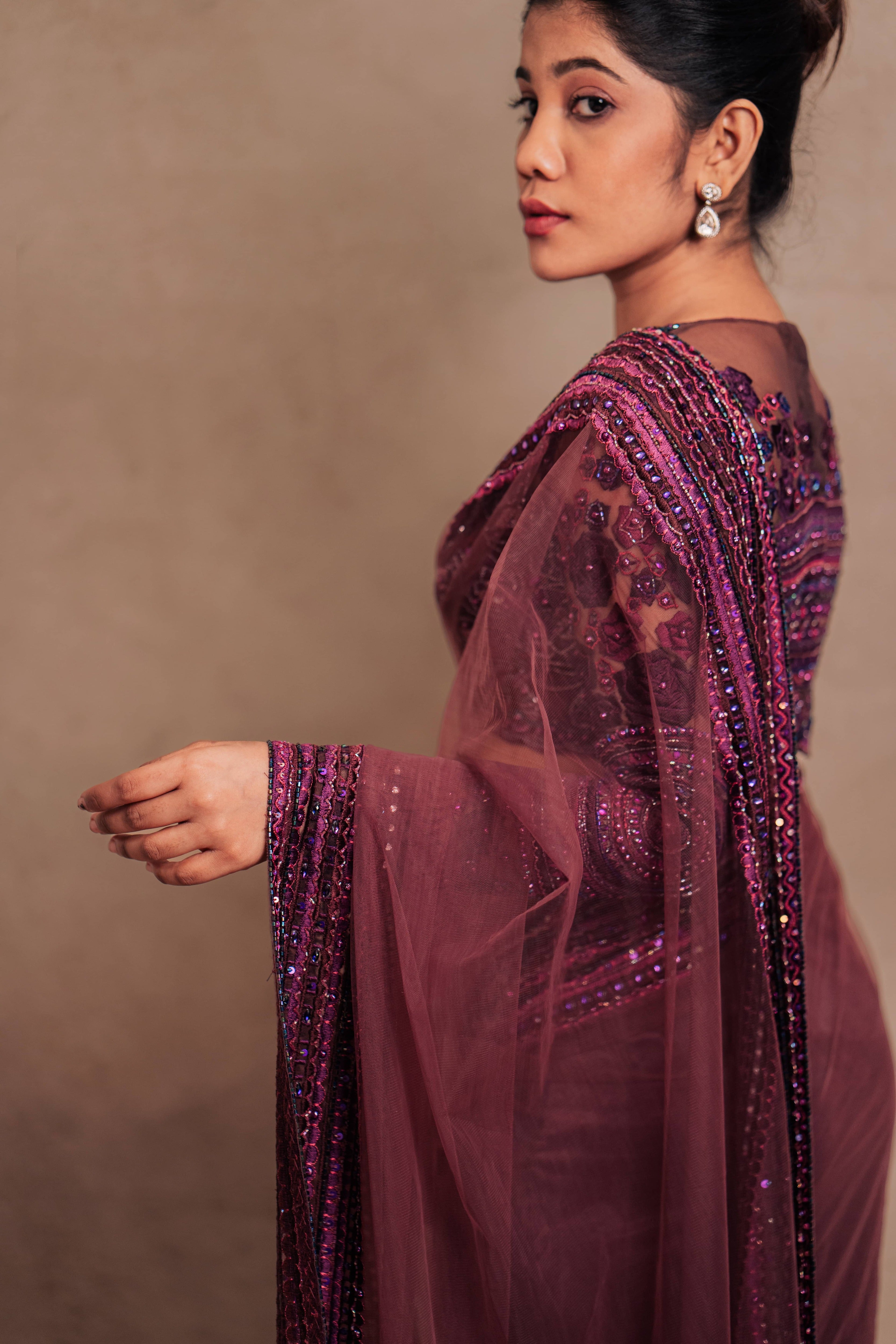 Jaina Parmar, known for recreating looks of actress Nayanthara is seen here in a purple net saree with heavily embellished border and full sleeved blouse with stone and resham work posing for closeup of saree pallu and border design