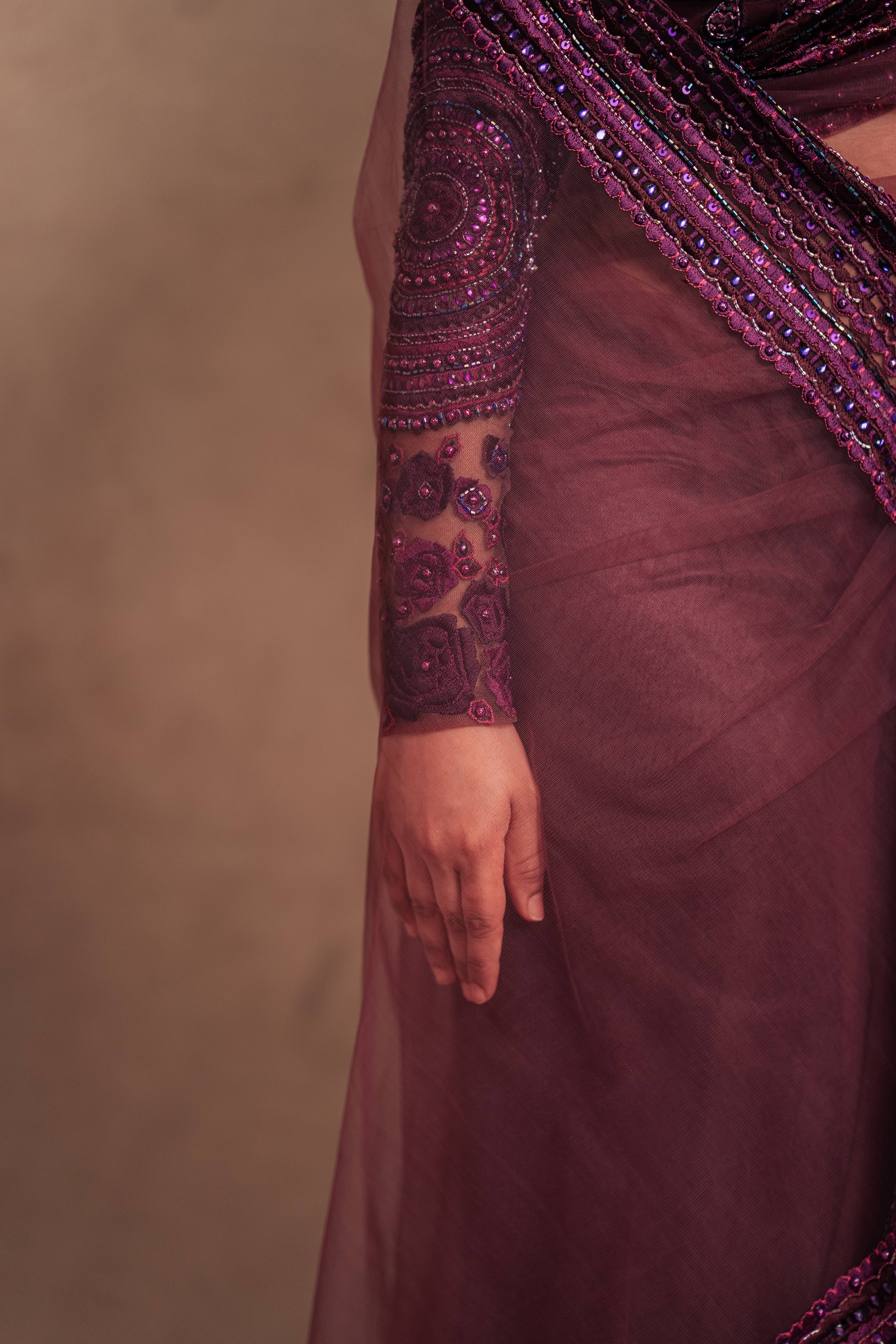 Jaina Parmar, known for recreating looks of actress Nayanthara is seen here in a purple net saree with heavily embellished border and full sleeved blouse with stone and resham work posing for front sleev