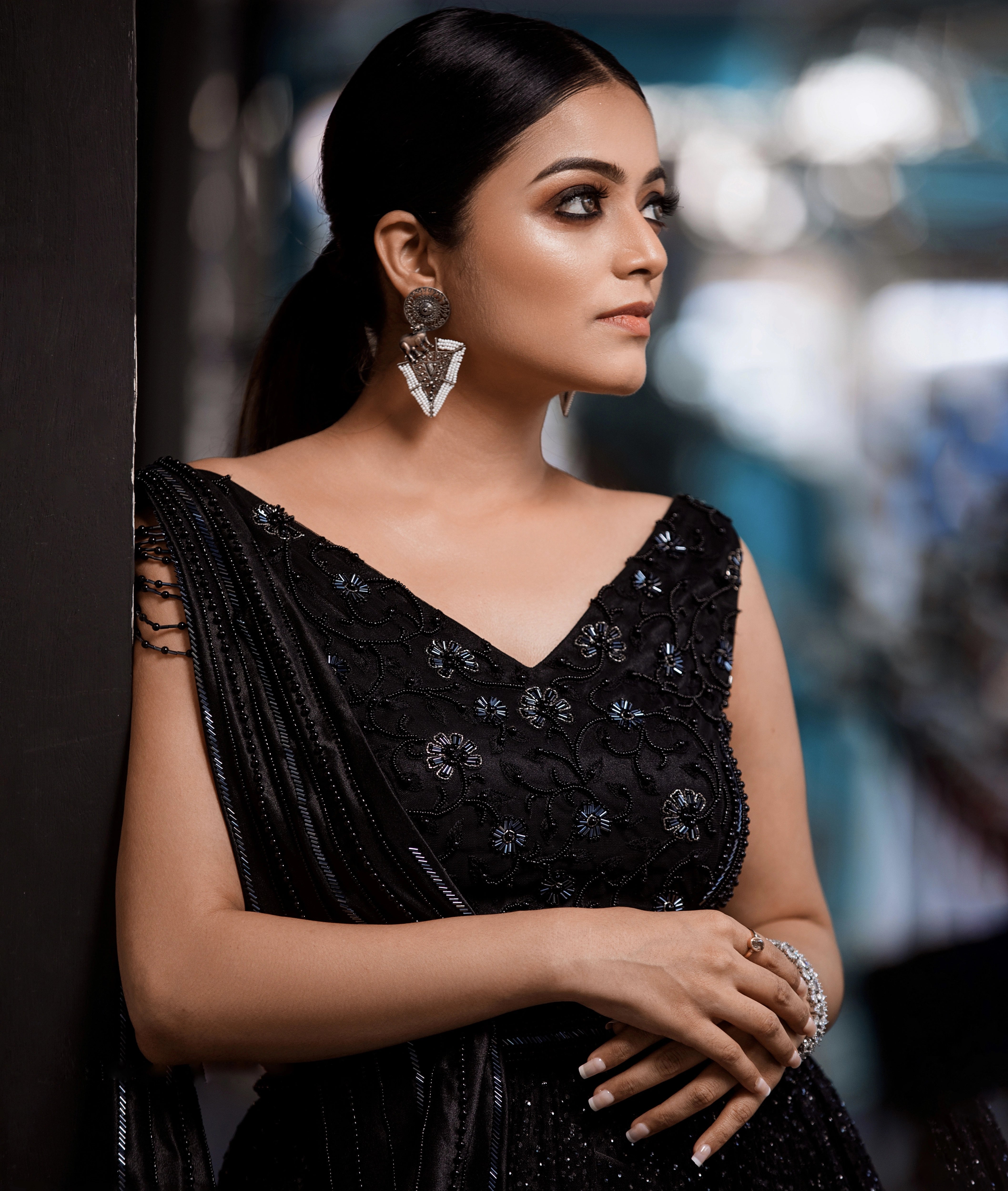 Janani Iyer in a leaning pose in a black net and satin gown with handcrafted drape, intricately designed with cutdana, sequins and beads by team Archana Karthick.