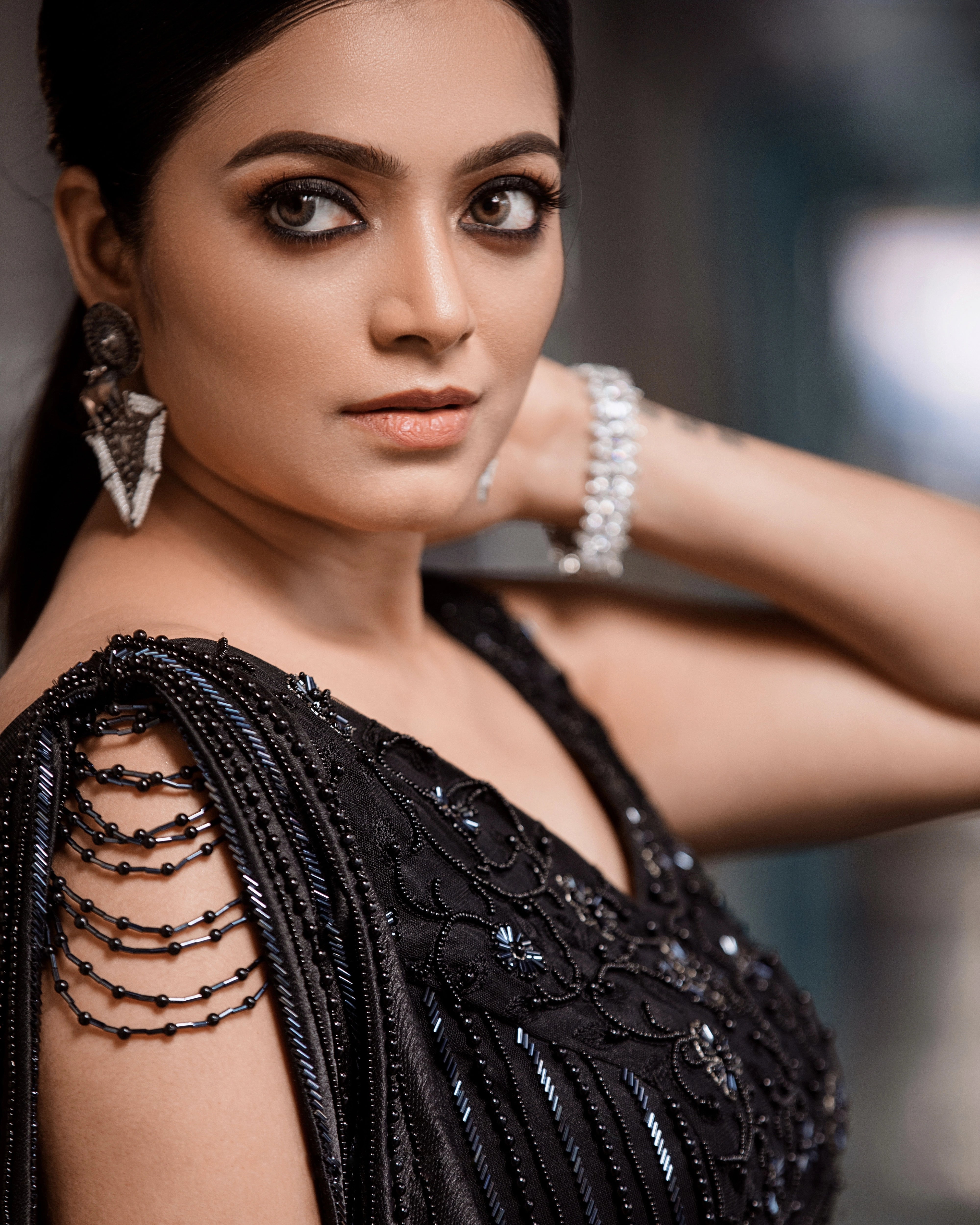 Janani Iyer looking right in a black net and satin gown with handcrafted drape, intricately designed with cutdana, sequins and beads by team Archana Karthick.