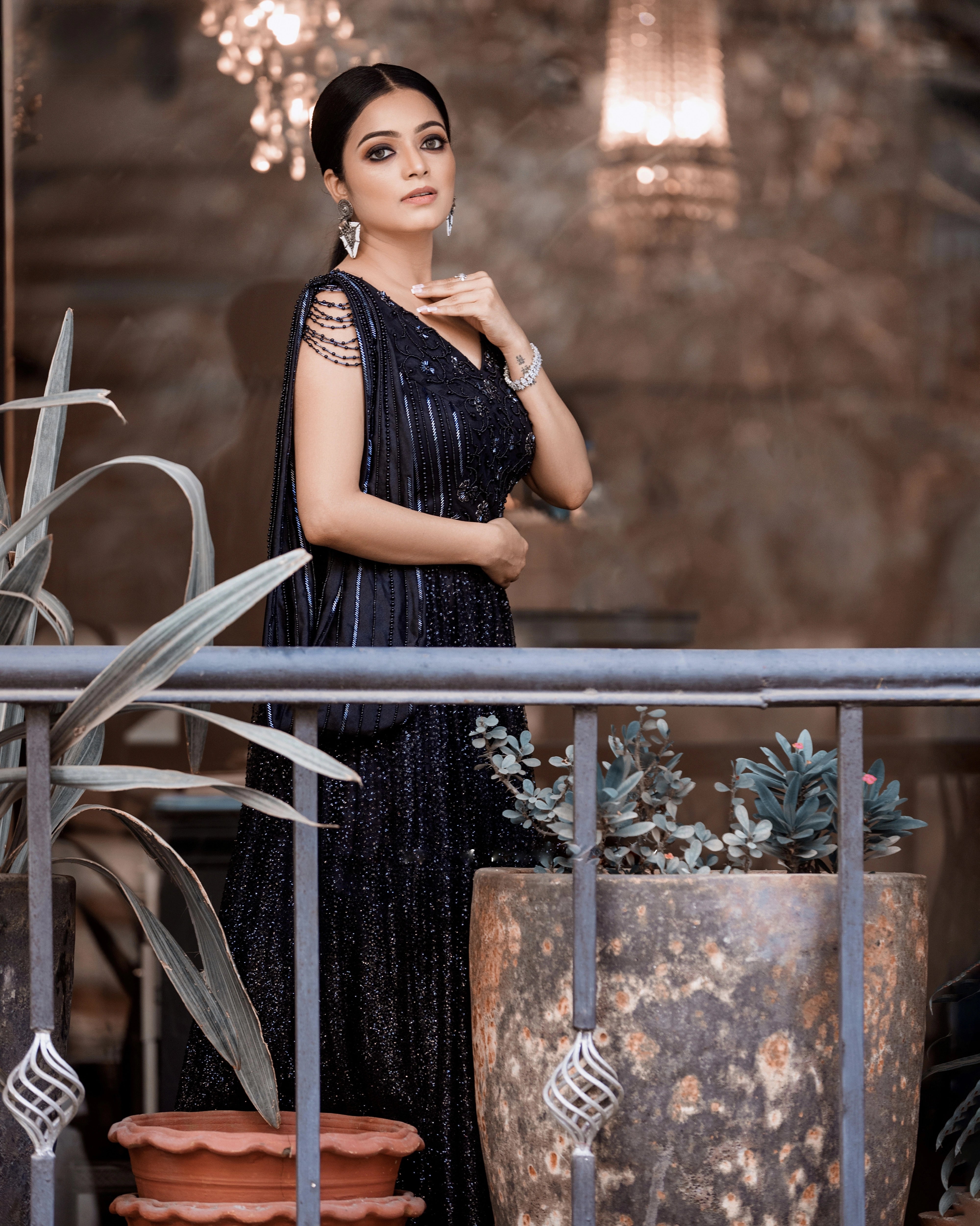 Janani Iyer posing in a black net and satin gown with handcrafted drape, intricately designed with cutdana, sequins and beads by team Archana Karthick.