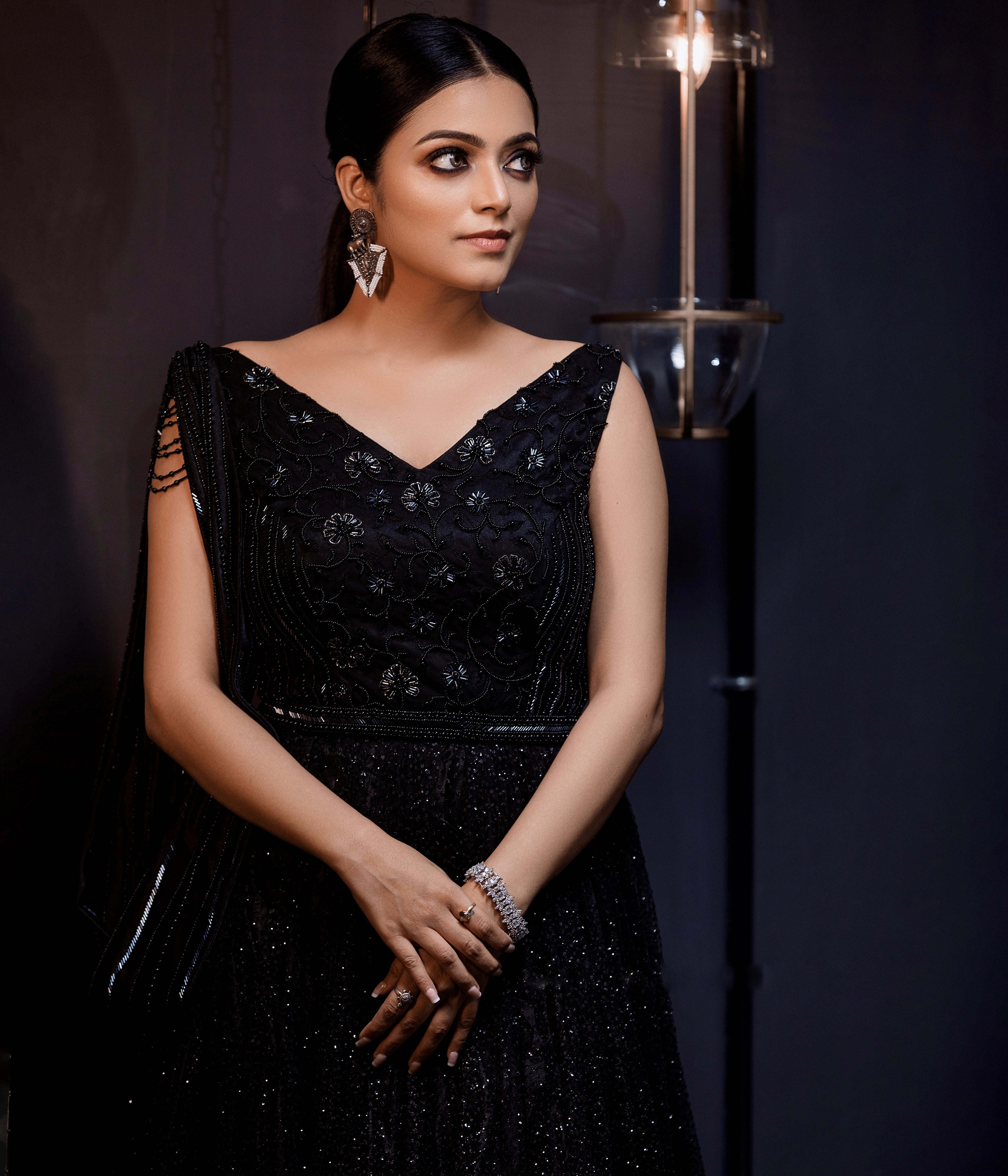 Janani Iyer showcasing front profile in a black net and satin gown with handcrafted drape, intricately designed with cutdana, sequins and beads by team Archana Karthick.