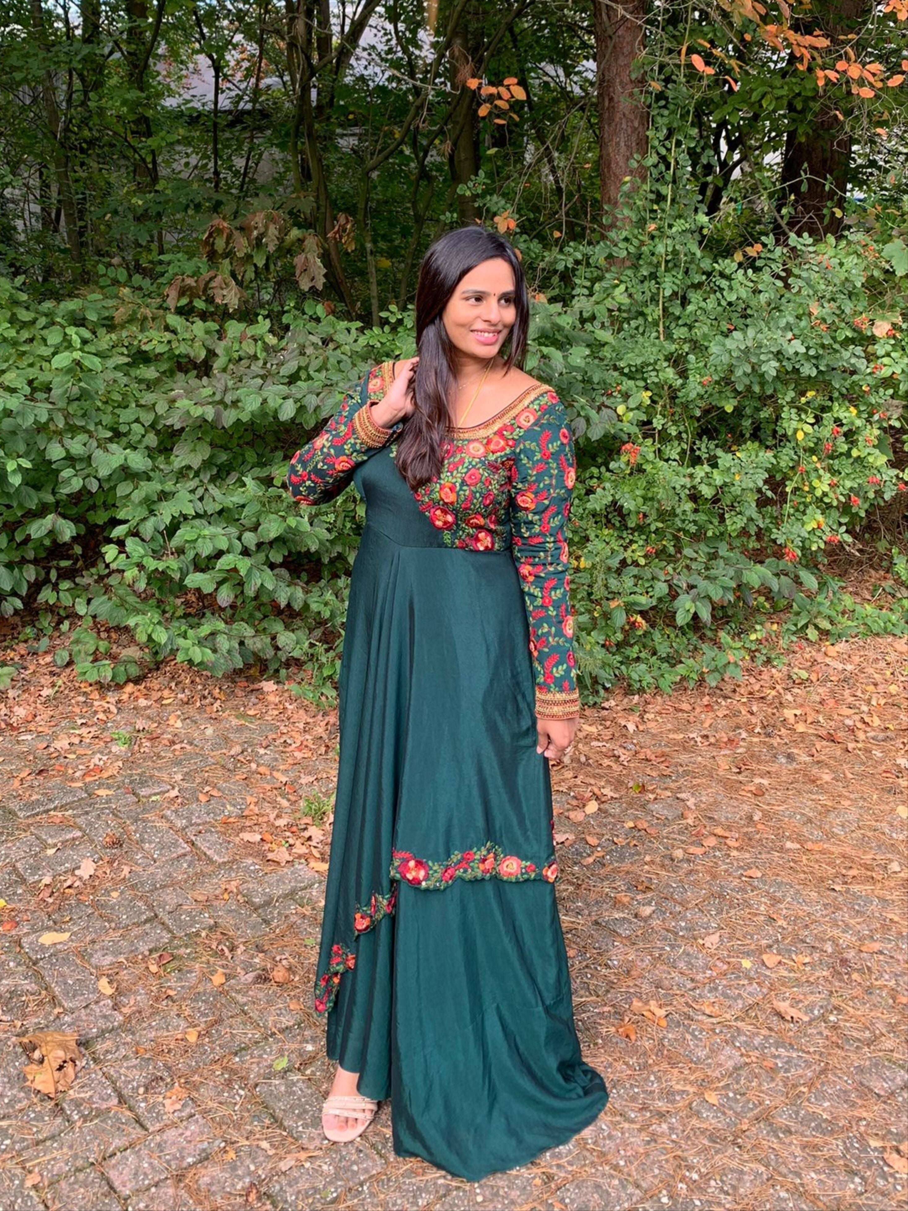 Kowsalya fro Buffalo, USA in an a green multi-layered anarkali designed by Archana Karthick. Looking away from the camera with one hand on hair.