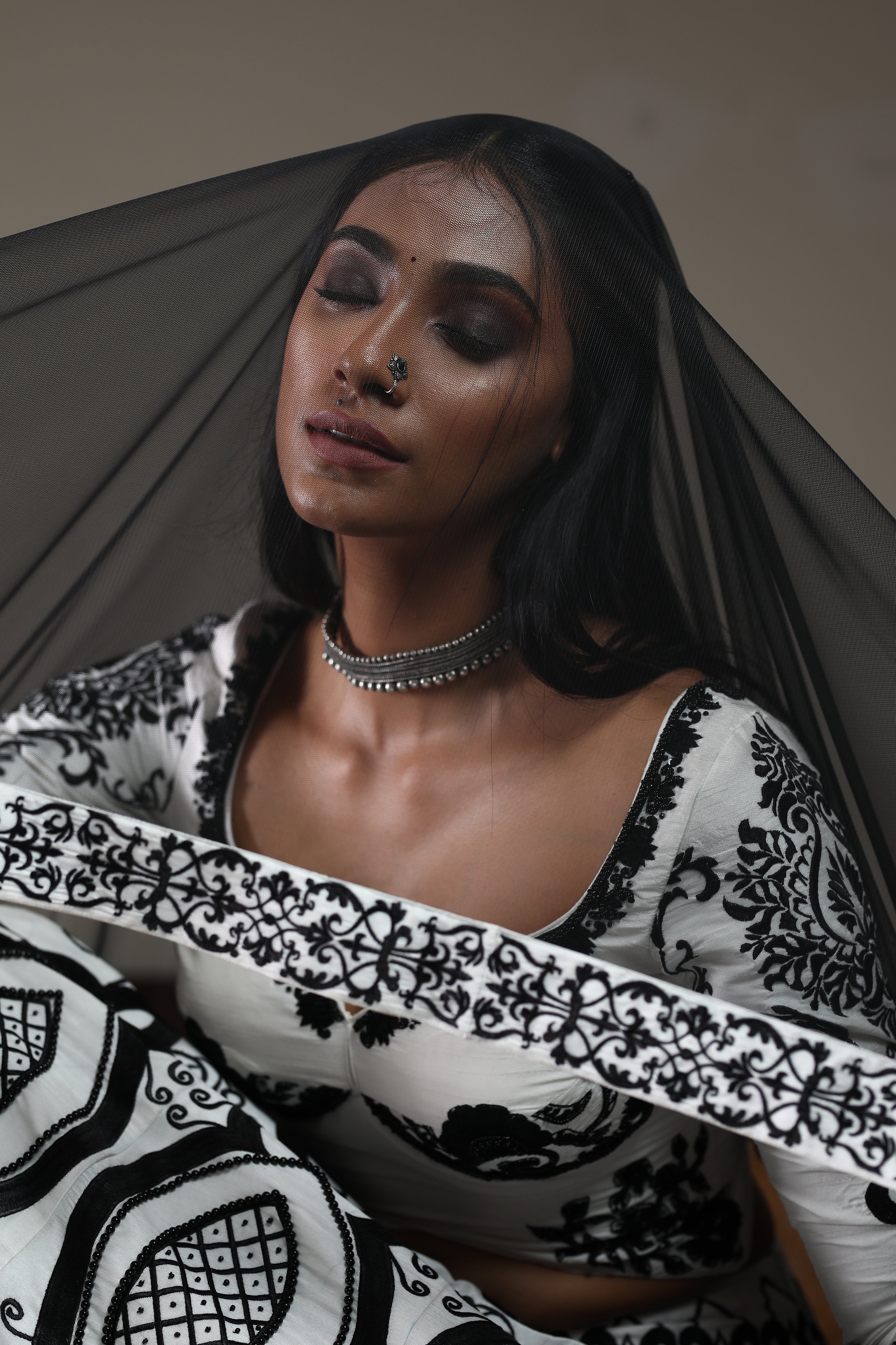 Miss India 2018 Anukreethy Vas in white raw sIlk lehenga with motifs in black velvet posing in a manner that highlights the net dupatta and the intricaies on the border if the dupatta and the lehenga and blouse. it is a closeup shot. This lehenga is designed by Archana Karthick. 