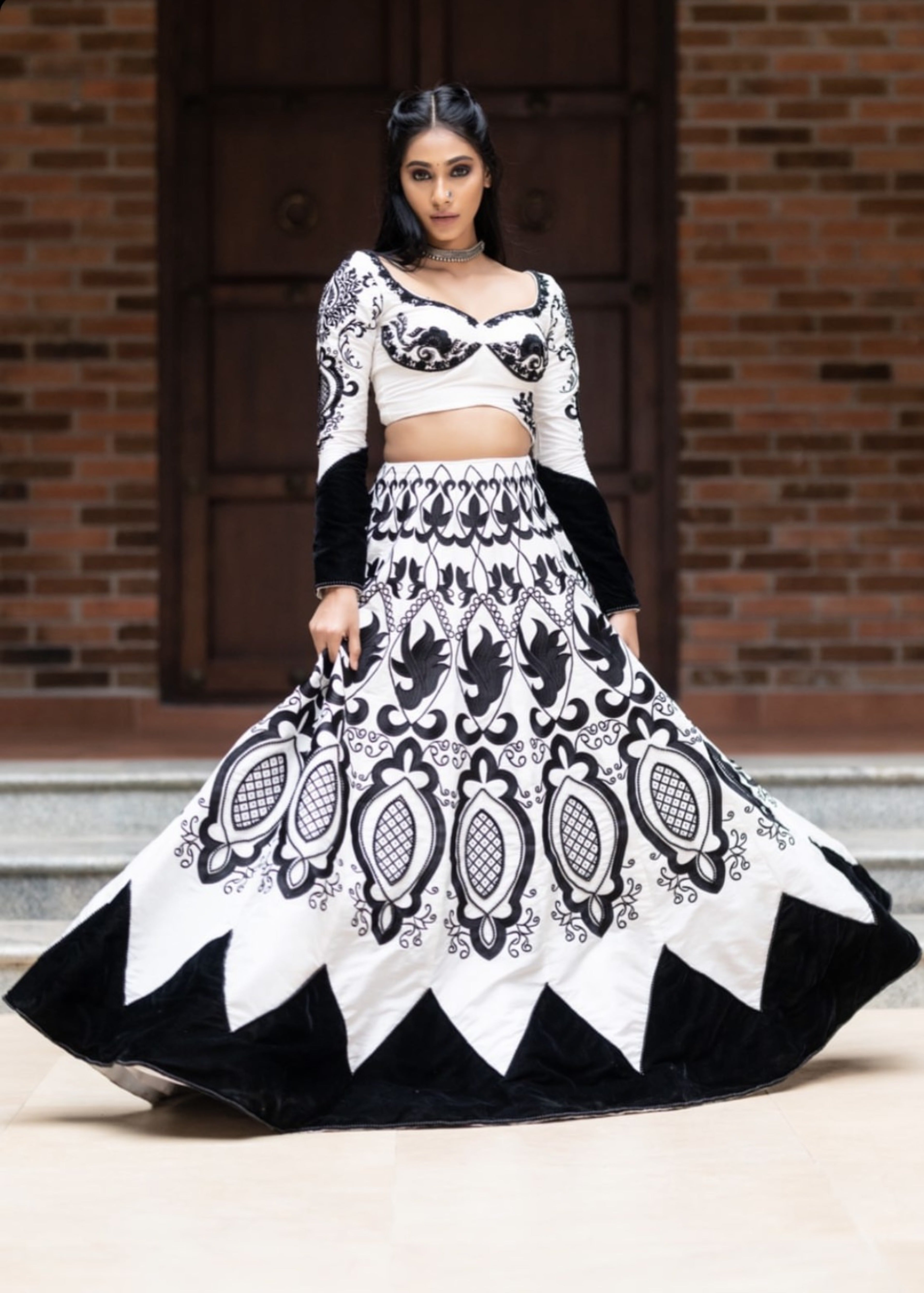Miss India 2018 Anukreethy Vas in white raw sIlk lehenga with motifs in black velvet posing mid twirl with a straight look at the lens. This lehenga is designed by Archana Karthick