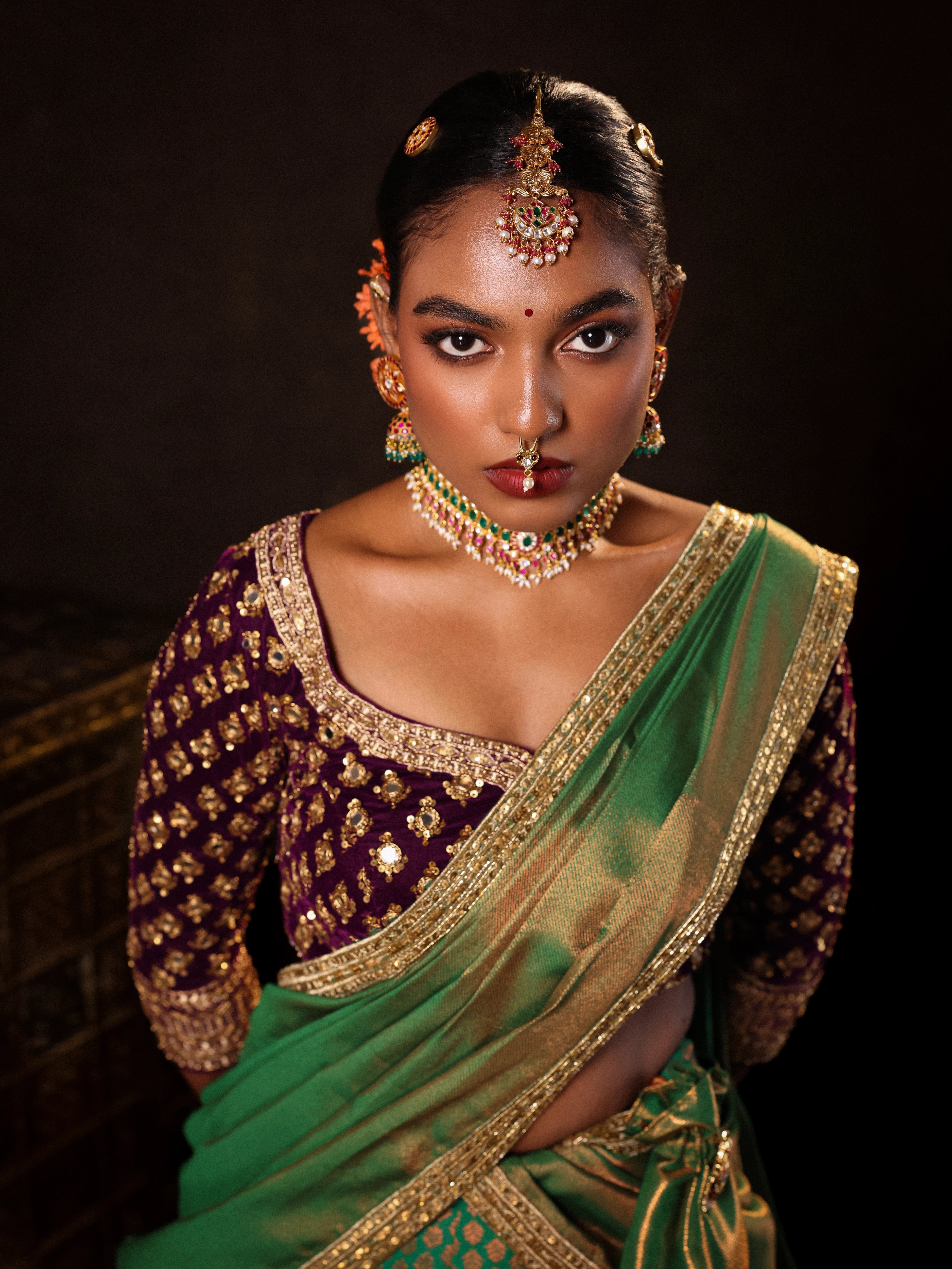 Model Ashika Crystal during photoshoot in a green and purple half saree set with a velvet blouse, tissue silk dupatta and brocade skirt handcrafted with zardozi, mirror, zari, cutdana and sequins. Team Archana Karthick completed the style with green glass bangles, a ring, a choker, jhumkas, nose ring and a maang tikka.