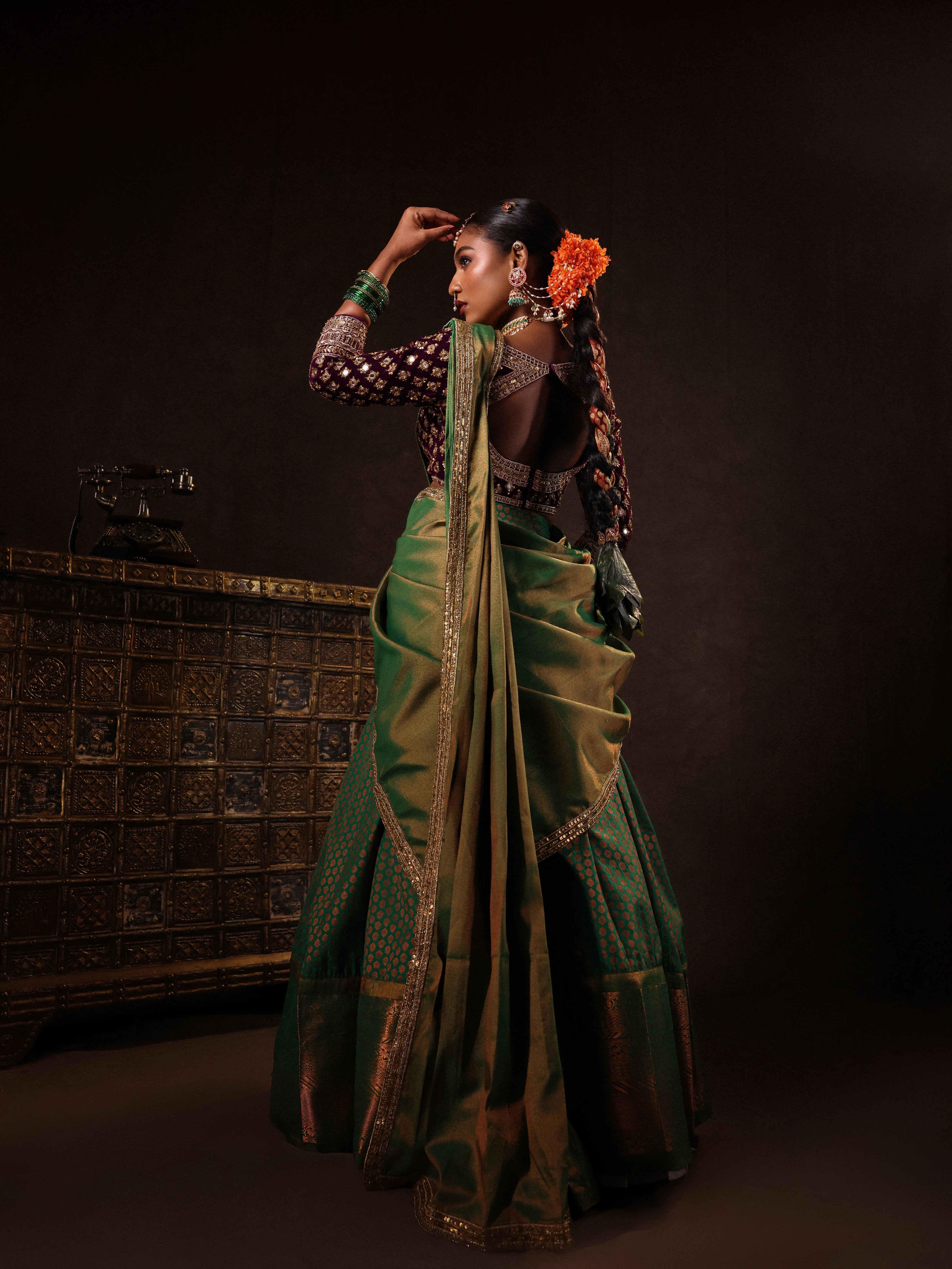 Model Ashika Crystal posing for back design in a green and purple half saree set with a velvet blouse, tissue silk dupatta and brocade skirt handcrafted with zardozi, mirror, zari, cutdana and sequins. Team Archana Karthick completed the style with green glass bangles, a ring, a choker, jhumkas, nose ring and a maang tikka.