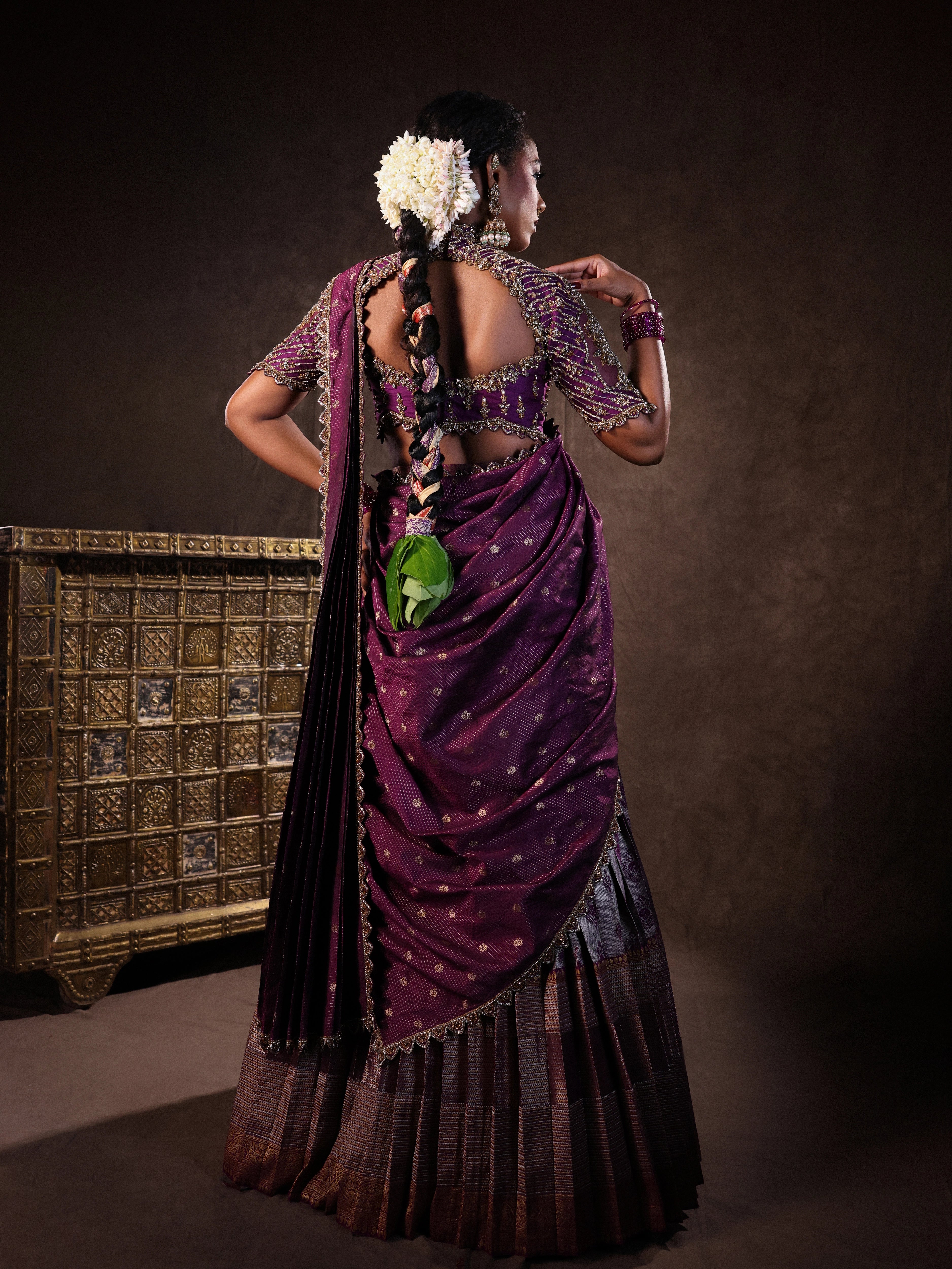 Model Ashika Crystal posing for back design in a silk half saree set in purple, handcrafted with zardozi, sequins and rhinestones. Team Archana Karthick completed the style with purple glass bangles, a ring, jhumkas, nose ring and a maang tikka.
