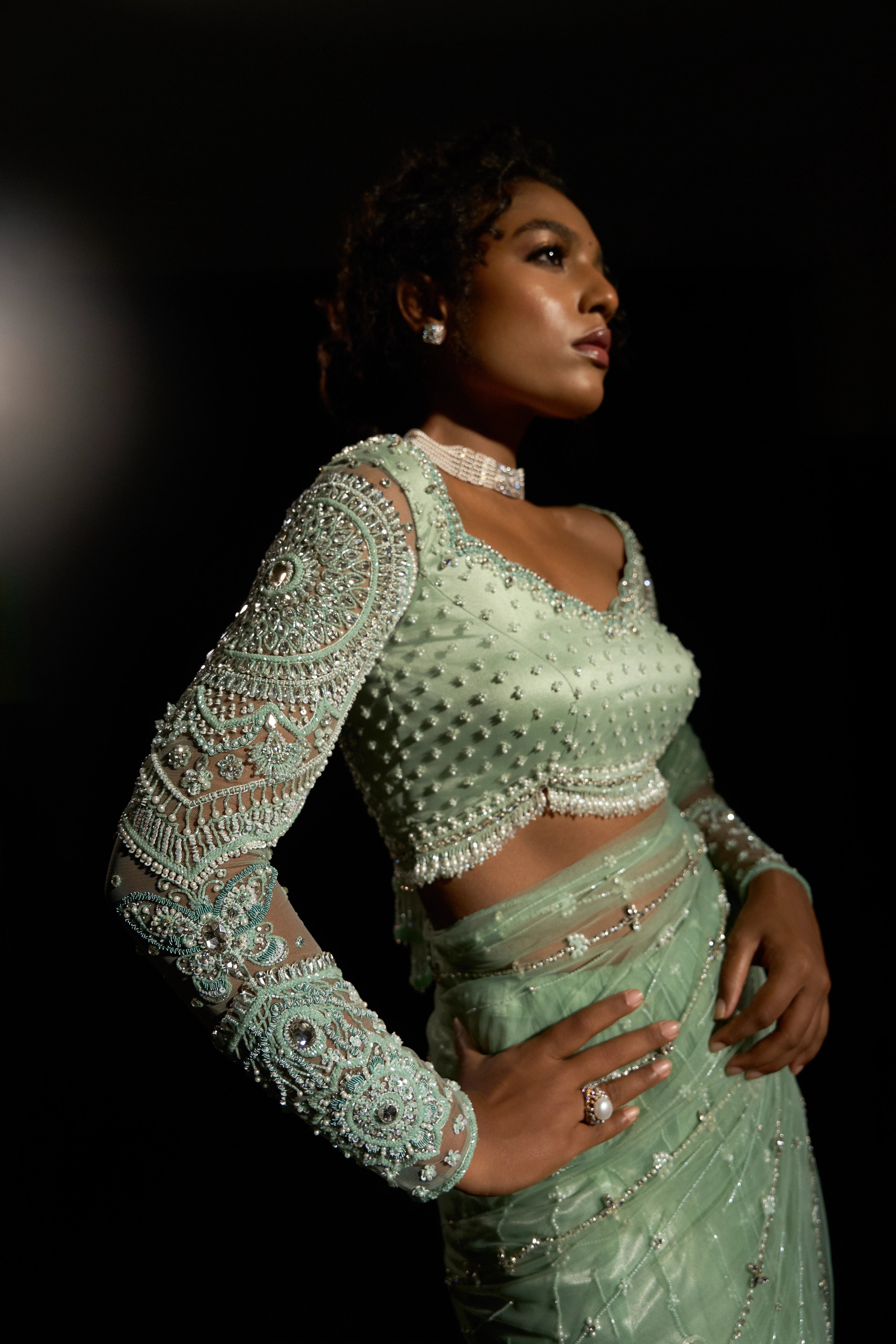 Model Ashika Crystal posing for the blouse and sleeve detailing in a green saree set intricately adorned with sequins, rhinestones, crystals and cutdana for "STARDUST" - A/W'25 saree collection by team Archana Karthick.