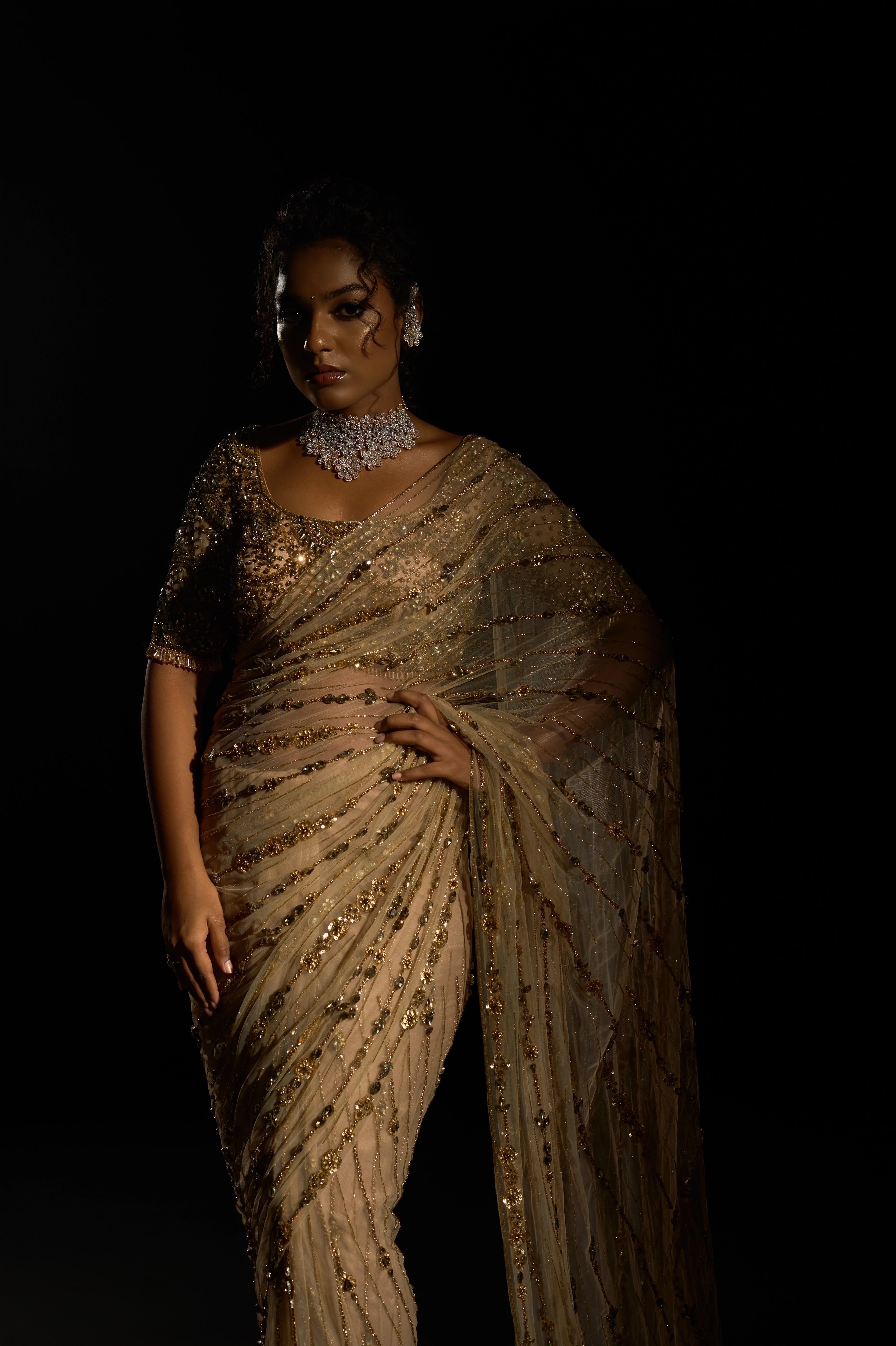Model Ashika Crystal posing in a gold saree set intricately adorned with sequins, rhinestones, crystals and cutdana for "STARDUST" - A/W'25 saree collection by team Archana Karthick.