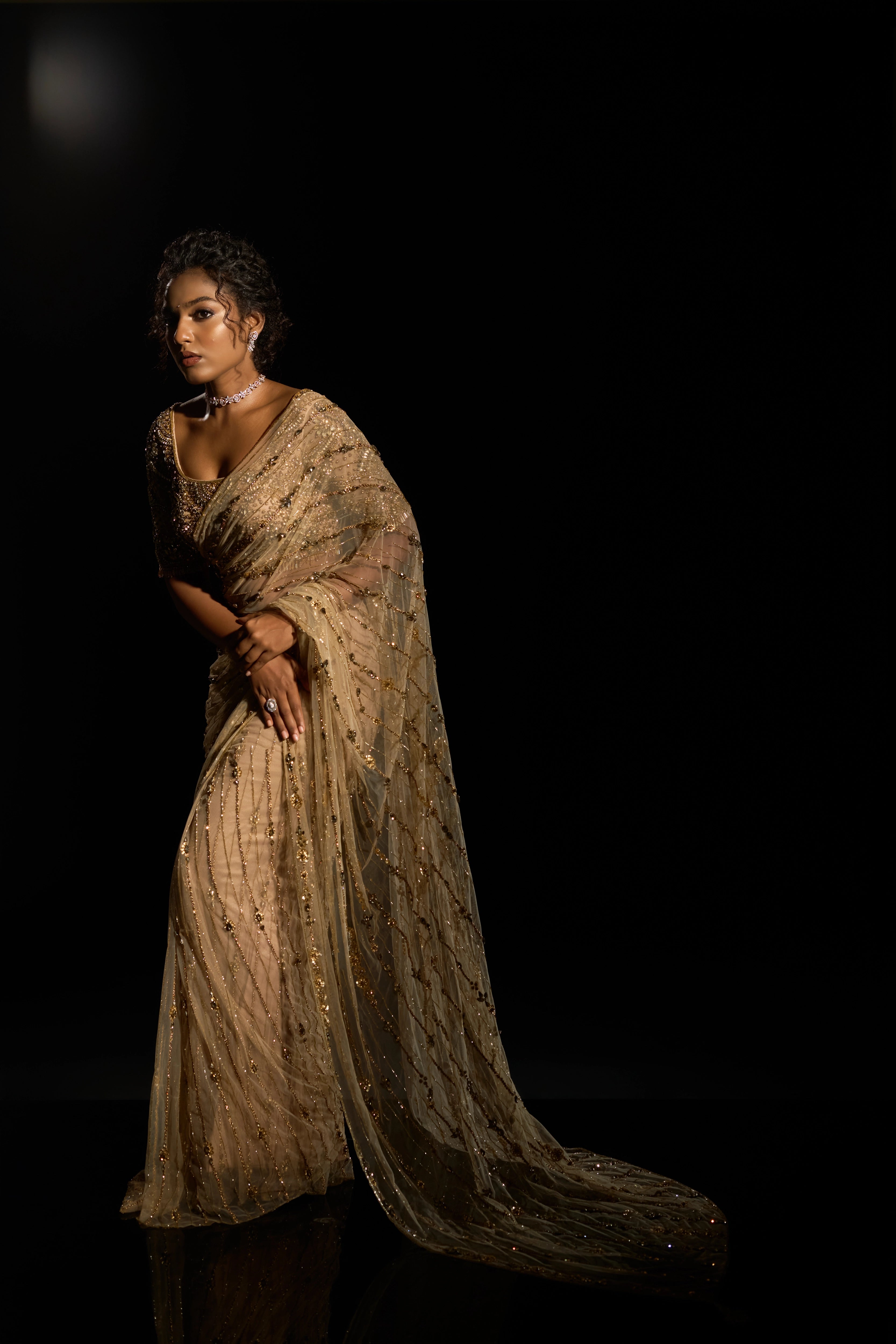 Model Ashika Crystal posing stylishly in a gold saree set intricately adorned with sequins, rhinestones, crystals and cutdana for "STARDUST" - A/W'25 saree collection by team Archana Karthick.