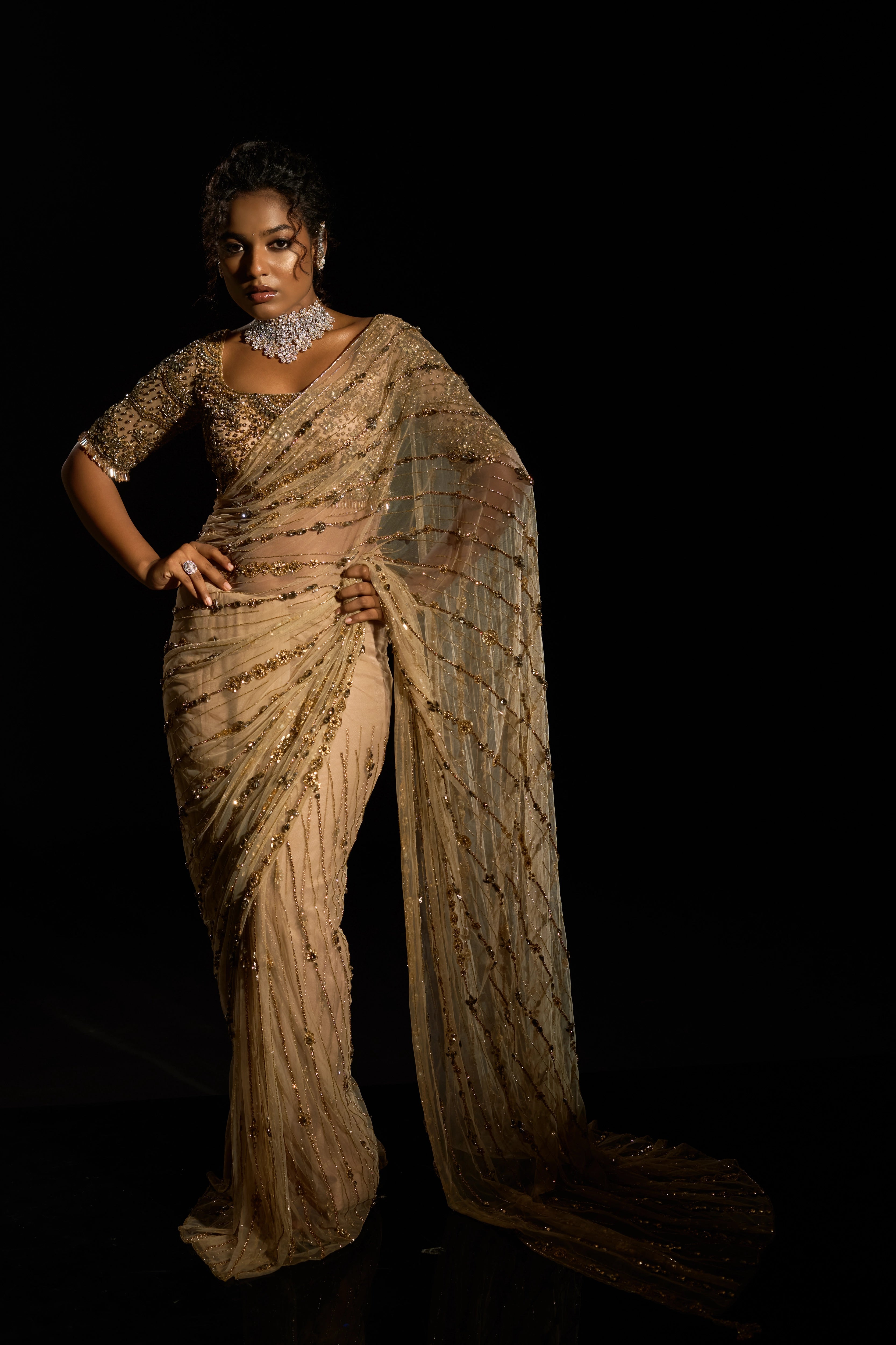 Model Ashika Crystal showcasing front profile in a gold saree set intricately adorned with sequins, rhinestones, crystals and cutdana for "STARDUST" - A/W'25 saree collection by team Archana Karthick.