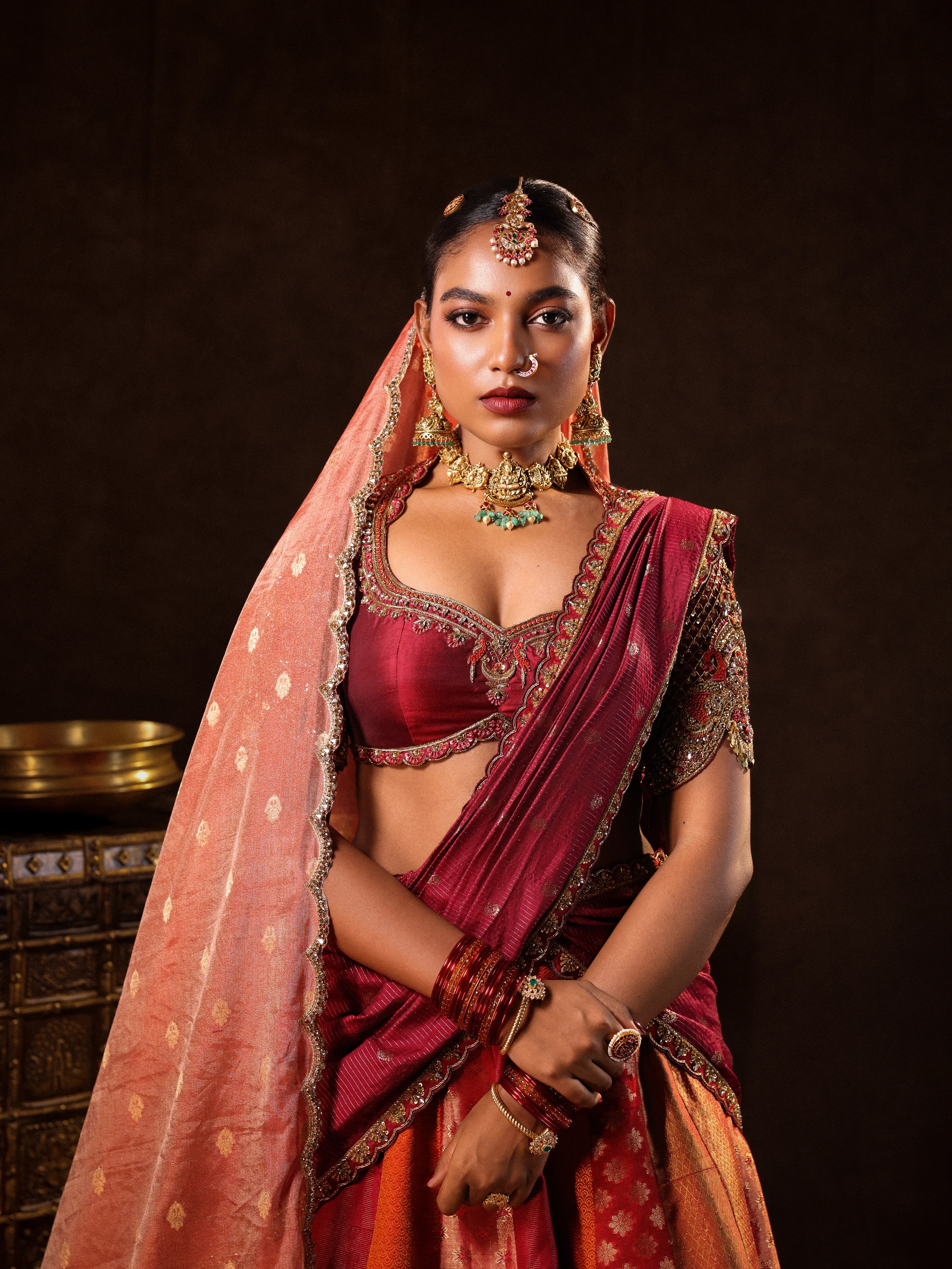 Model Ashika Crystal showcasing the veil, blouse front and dupatta in a red and orange silk half saree with a scalloped veil is handrcrafted with sequins, cutdana, resham, stones and exquisite hangings by team Archana Karthick