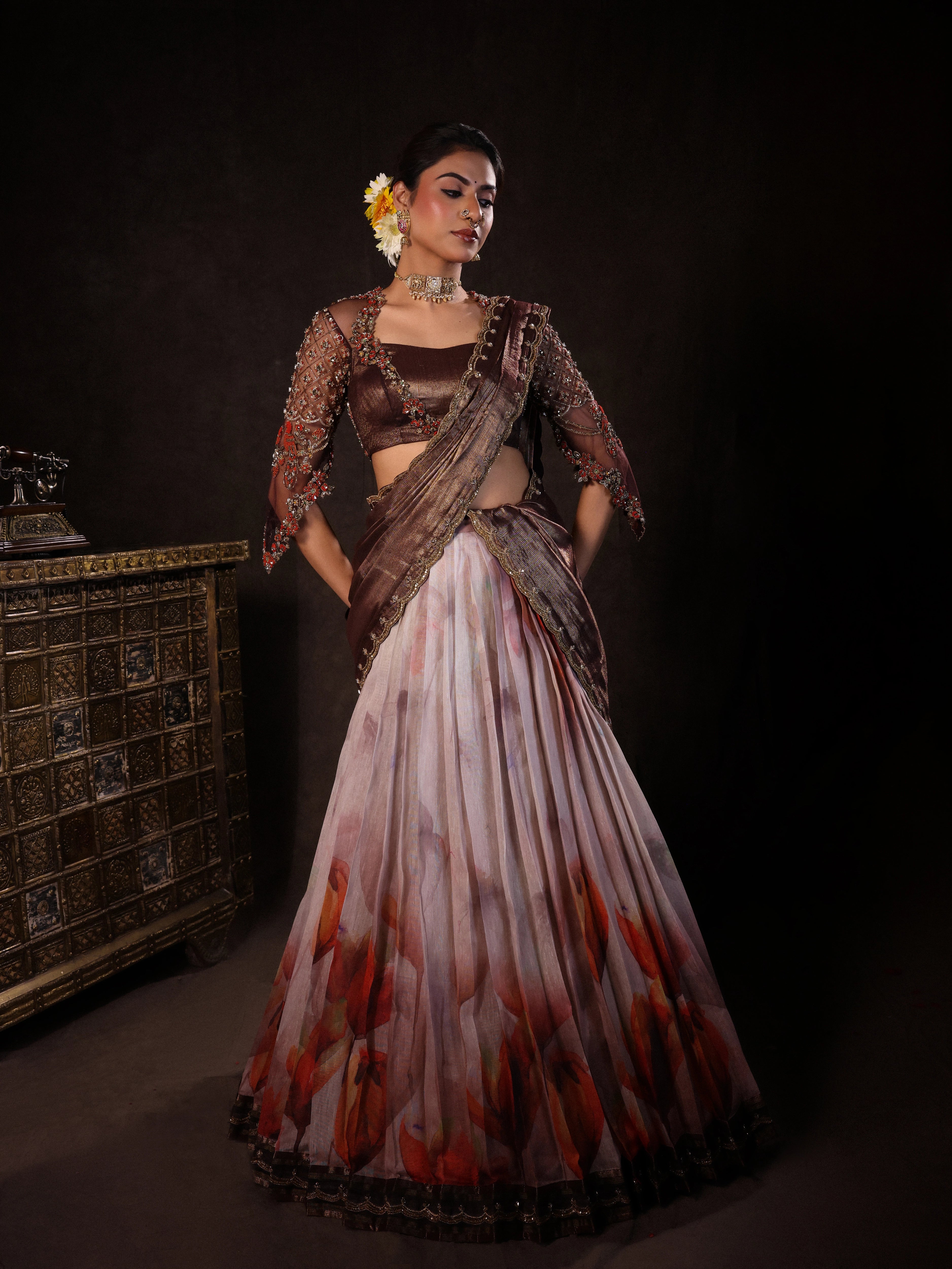 Model Dr Sree Advaita in a brown & printed ivory silk half saree set handcrafted with zardozi, resham, cutdana, sequins & rhinestones. Team Archana Karthick completed the style with brown glass bangles, a ring, jhumkas, nose ring and a maang tikka.