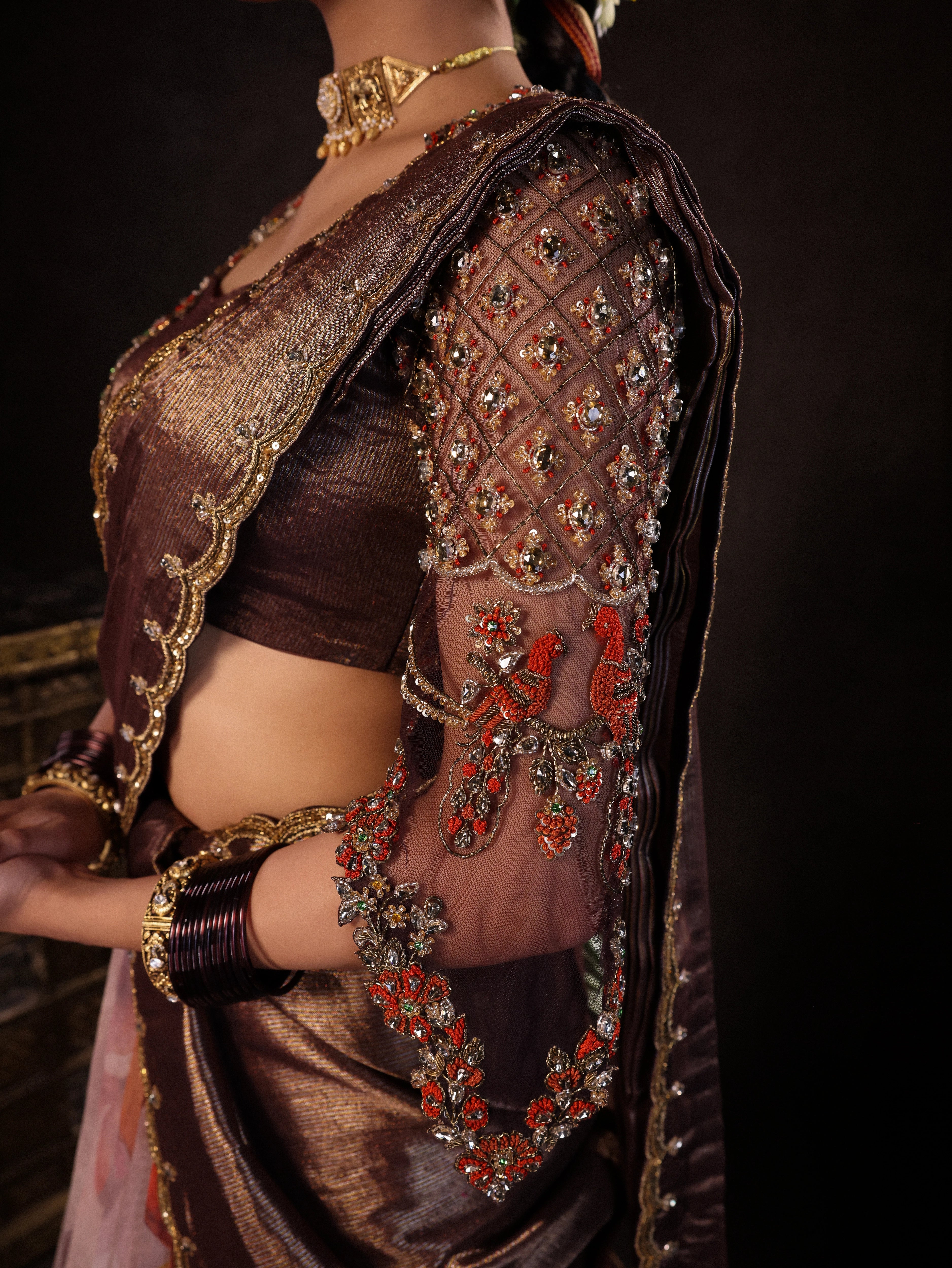 Model Dr Sree Advaita showcasing sleeve detailing in a brown & printed ivory silk half saree set handcrafted with zardozi, resham, cutdana, sequins & rhinestones. Team Archana Karthick completed the style with brown glass bangles, a ring, jhumkas, nose ring and a maang tikka.