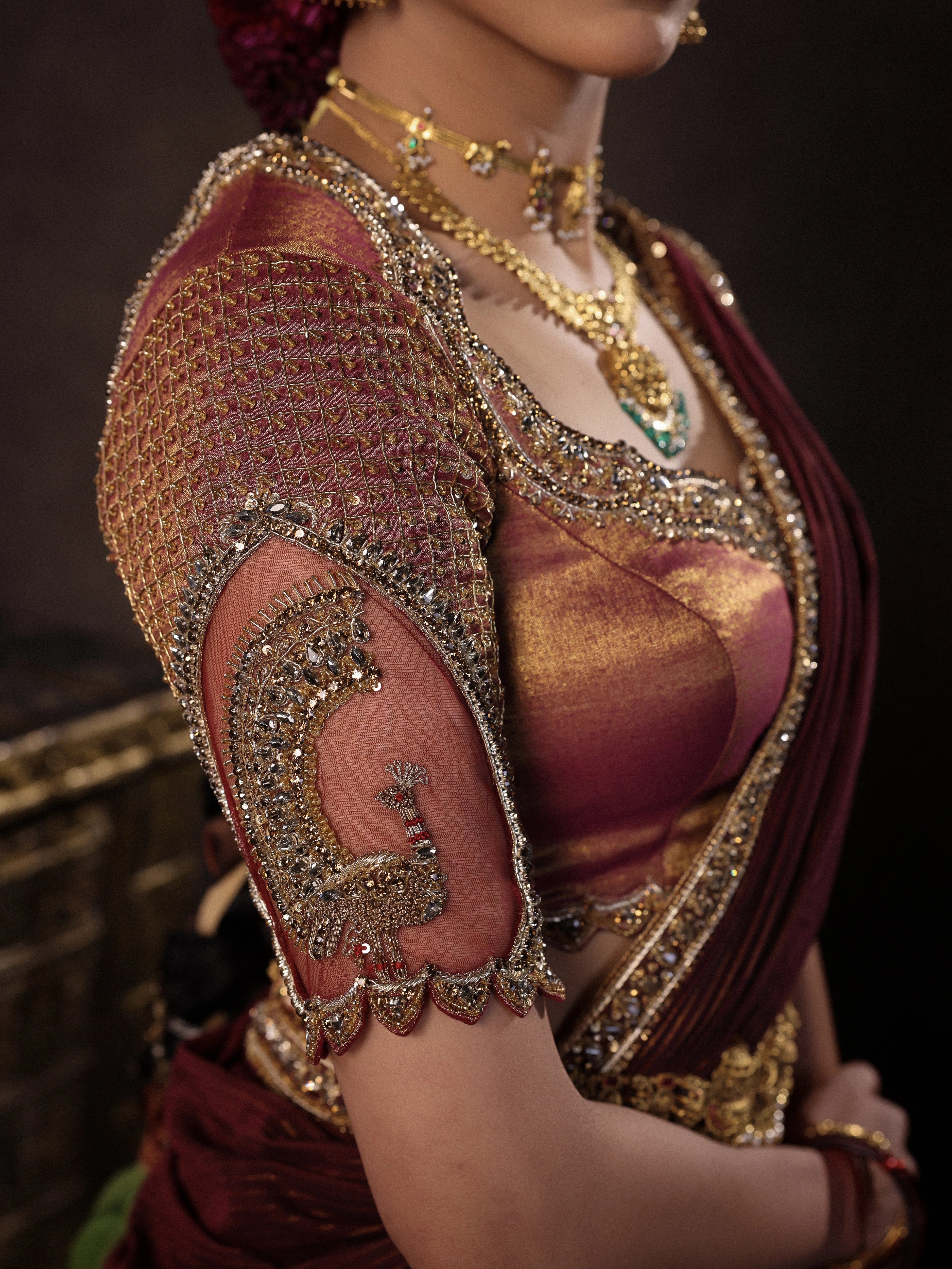 Model Dr Sree Advaita showcasing sleeve & neckline in a brownish maroon silk half saree set intricately handcrafted with zardozi, resham, cutdana, sequins & rhinestones. Team Archana Karthick completed the style with maroon glass bangles, a ring, jhumkas, nose ring and a maang tikka.