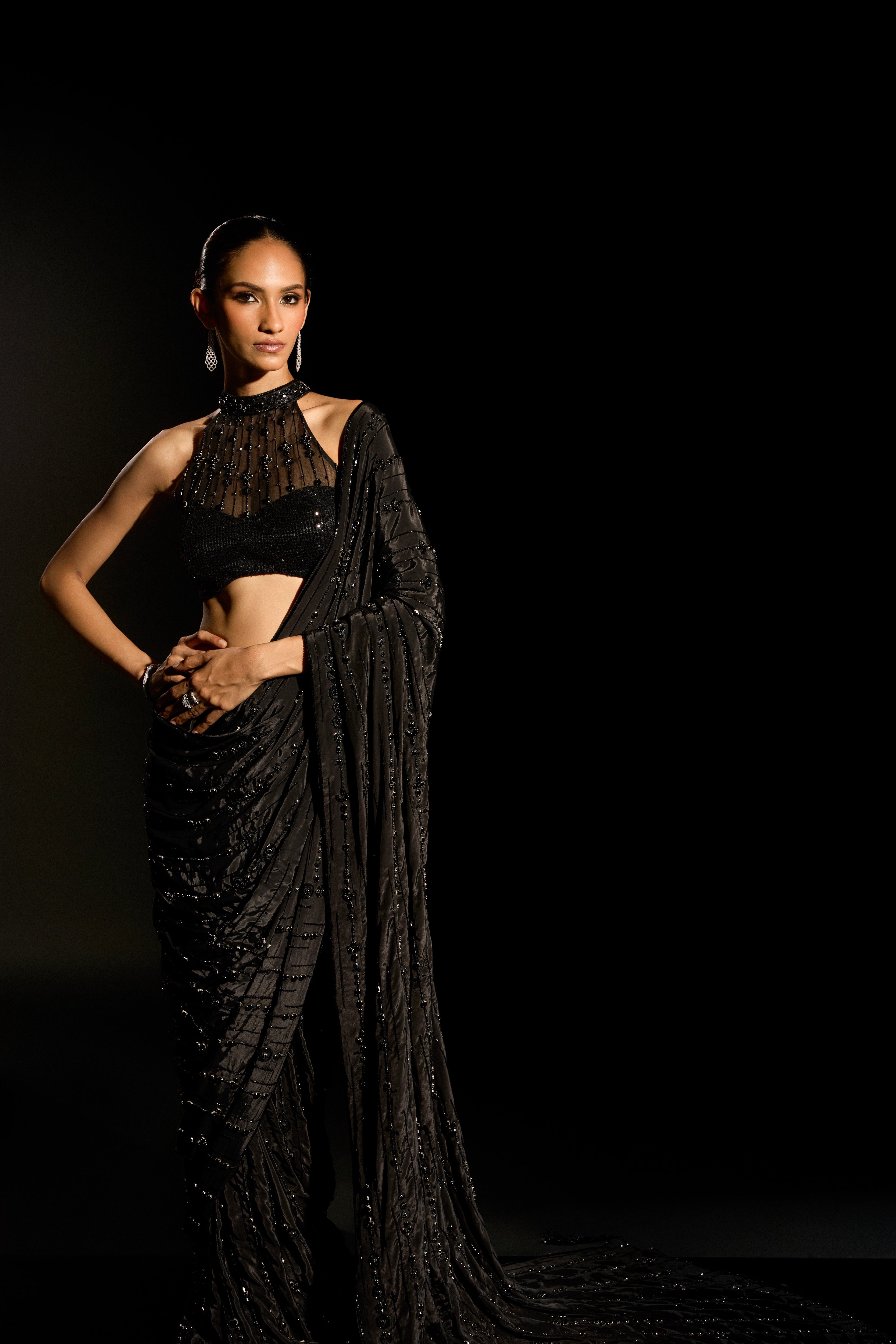 Model Esha Gohil posing for a full shot during photoshoot in a black saree set is intricately adorned with sequins, rhinestones and cutdana for "STARDUST" - A/W'25 saree collection by team Archana Karthick.