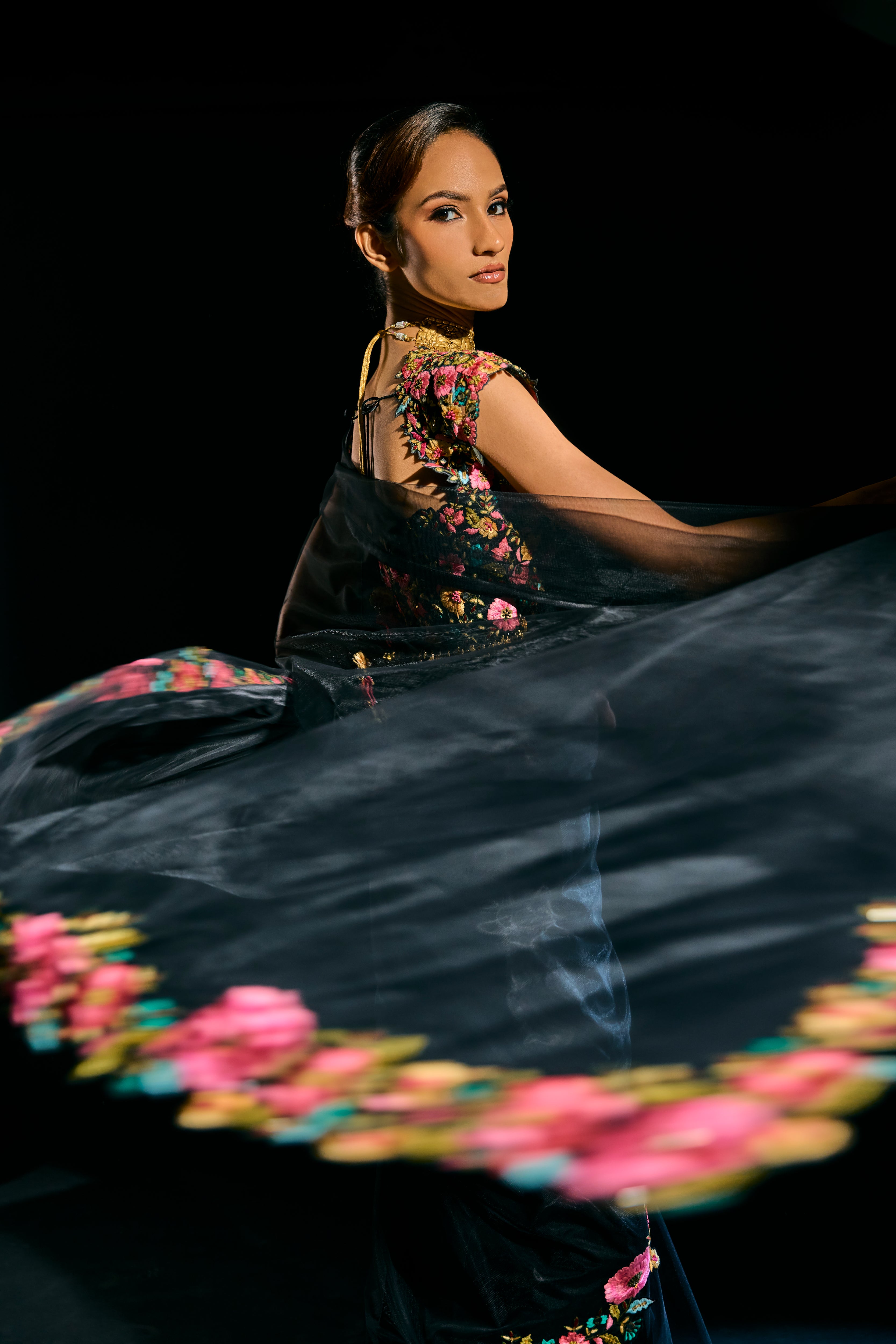 Model Esha Gohil posing in black tulle drape and embroidered with floral resham that gleam like whispers in the dark. Handcrafted for "HAZE" - A/W'25 capsule collection by Archana Karthick.