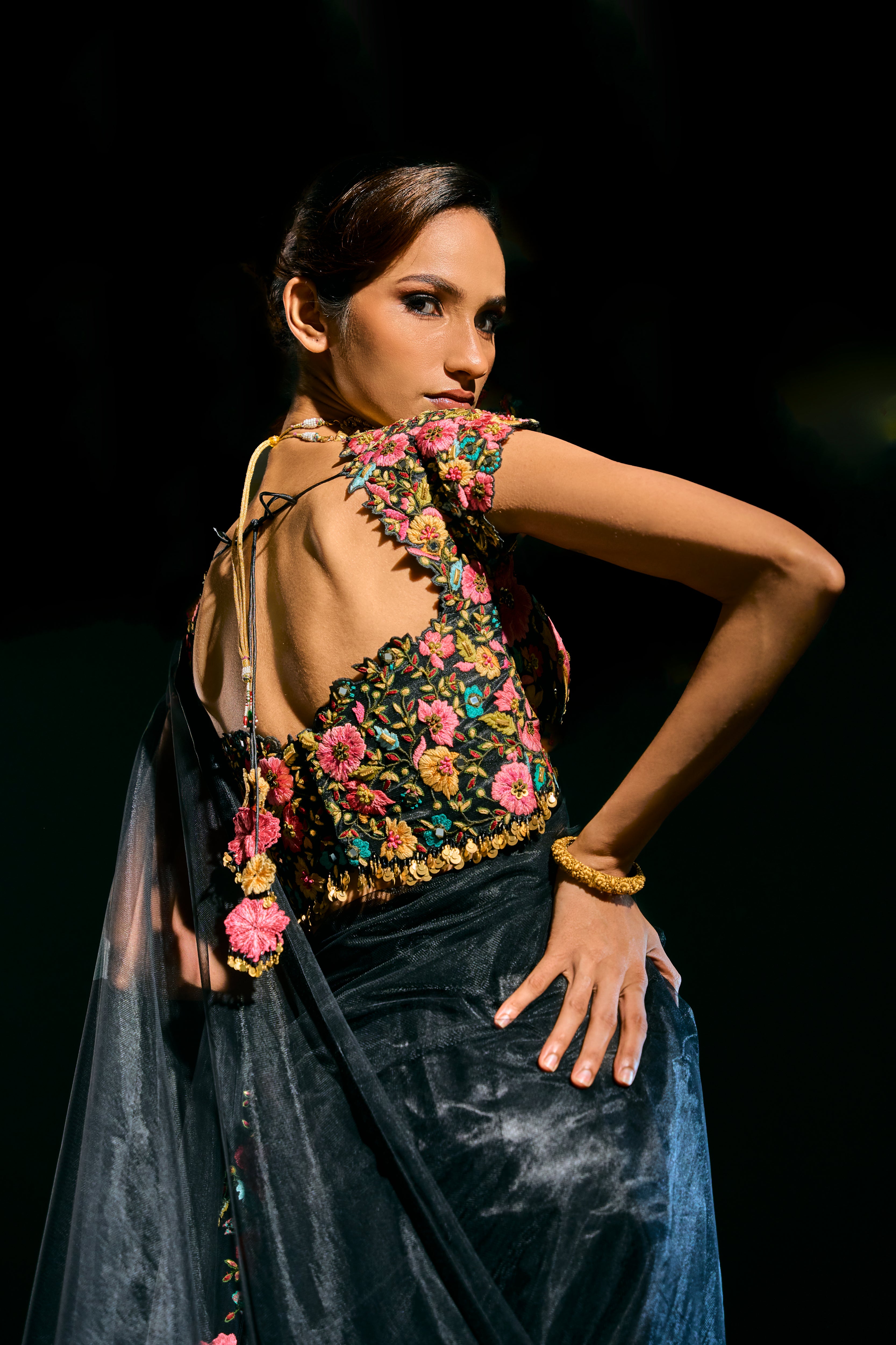 Model Esha Gohil showcasing back blouse design in black tulle drape and embroidered with floral resham that gleam like whispers in the dark. Handcrafted for "HAZE" - A/W'25 capsule collection by Archana Karthick.