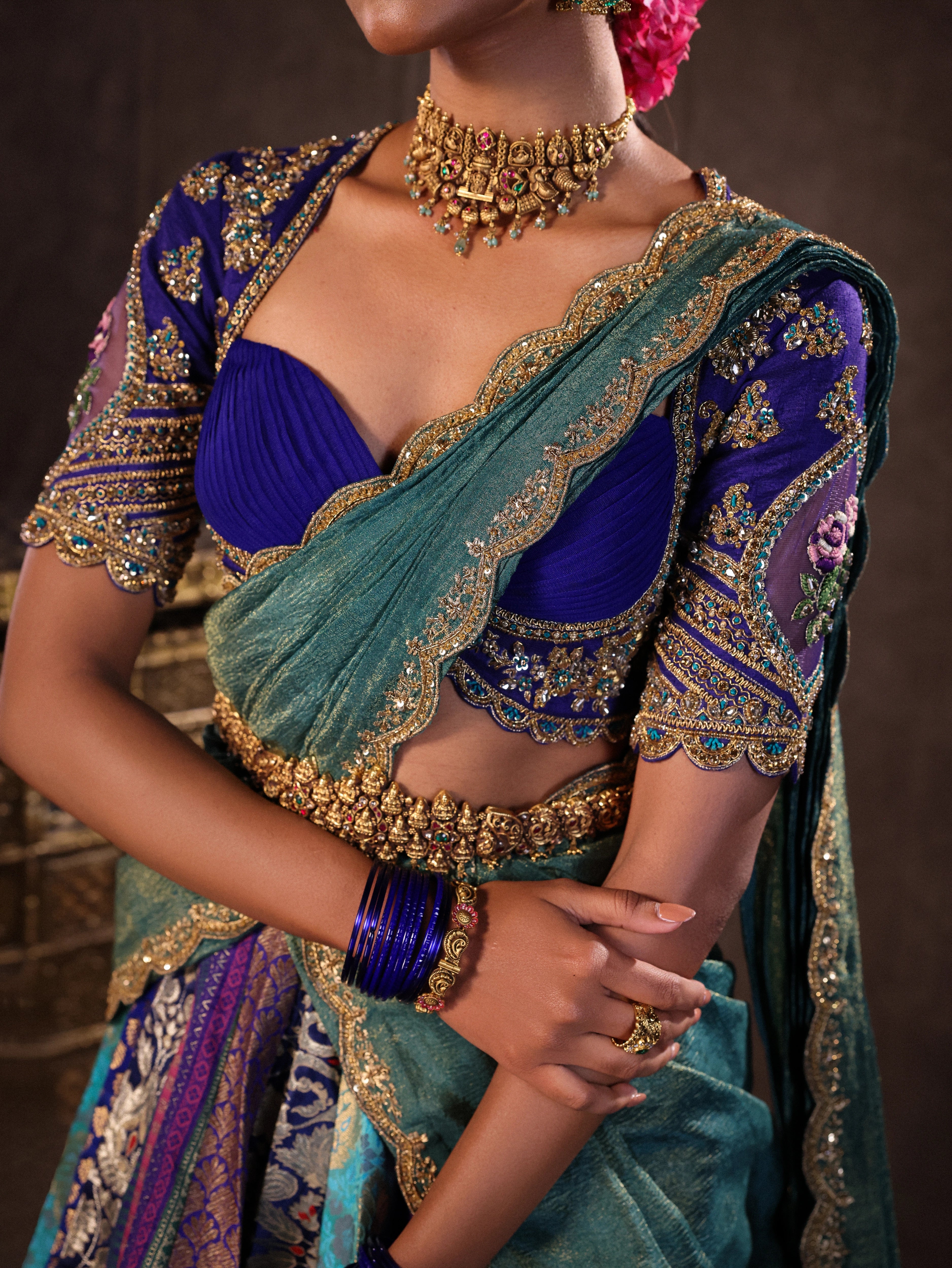 Model Gayathri Dhanasekar in a closeup shot in a brocade, raw silk and tissue silk half saree set in shades of blue handcrafted with zardozi, resham, sequins and rhinestones. Team Archana Karthick completed the style with blue glass bangles, a ring, a choker, jhumkas, nose ring and a maang tikka.