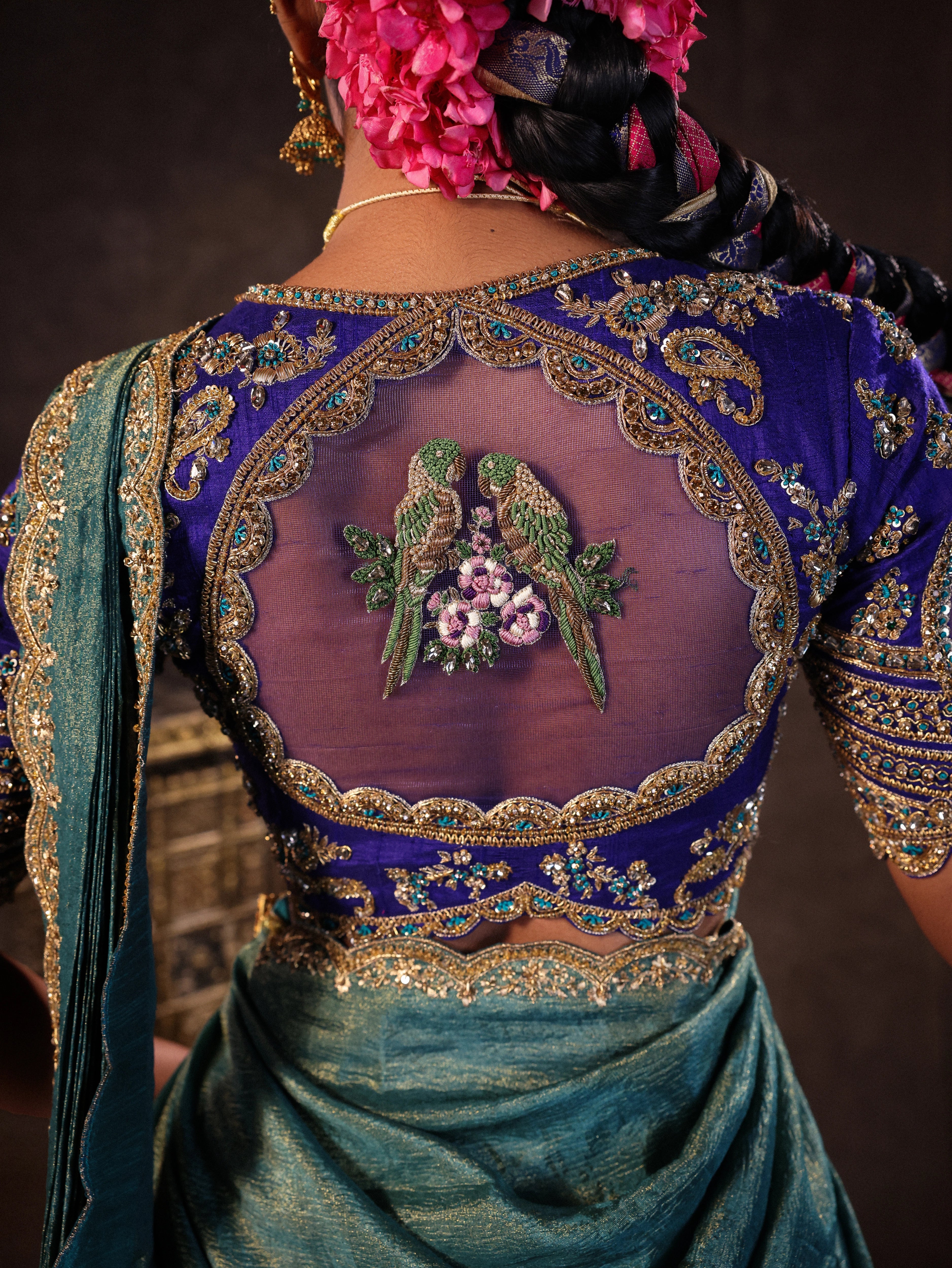 Model Gayathri Dhanasekar showcasing back blouse design in a brocade, raw silk and tissue silk half saree set in shades of blue handcrafted with zardozi, resham, sequins and rhinestones. Team Archana Karthick completed the style with blue glass bangles, a ring, a choker, jhumkas, nose ring and a maang tikka.