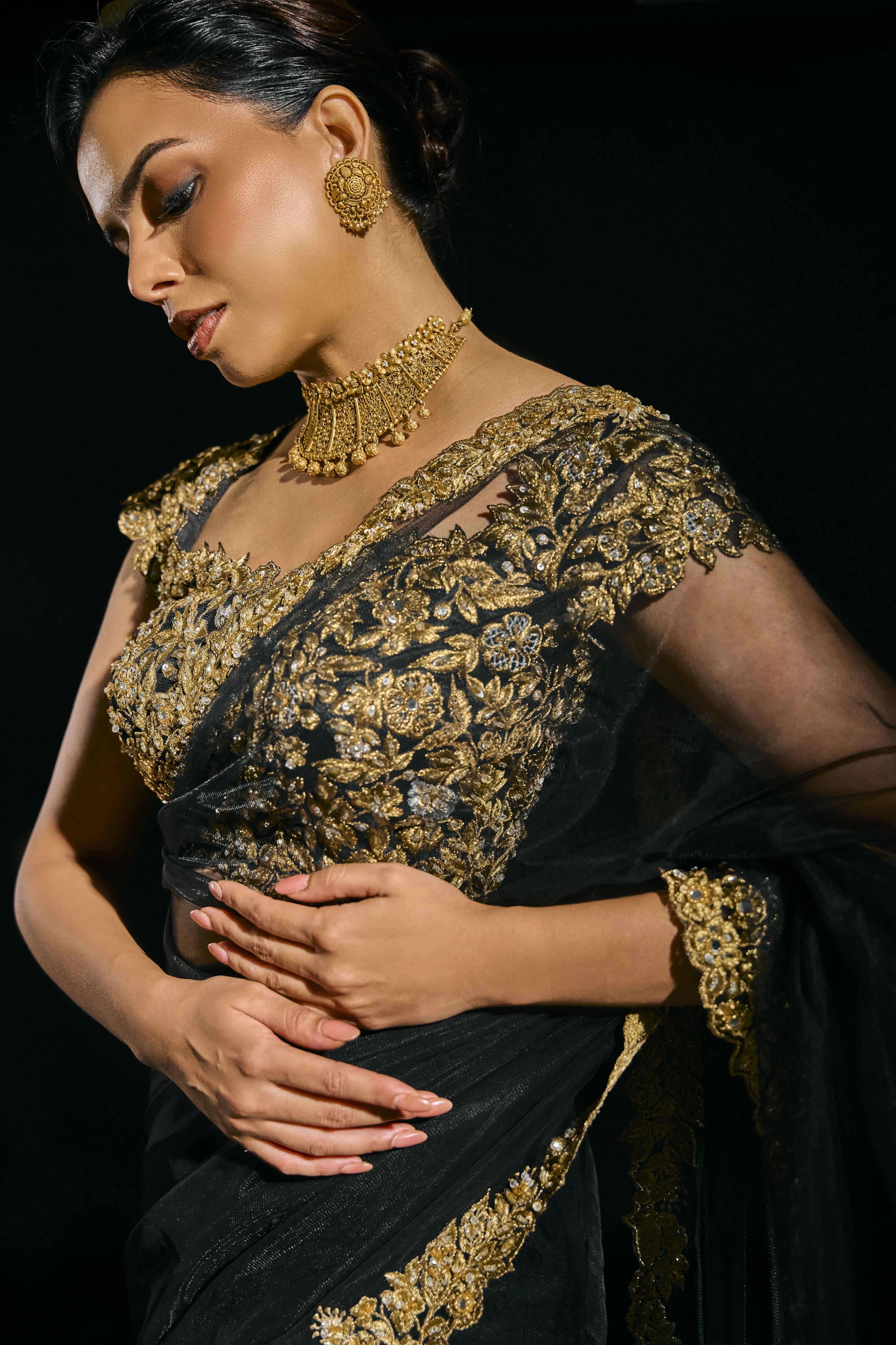 Model Jane C Thompson in a black net saree showcasing the gold blouse, handcrafted with zari, zardosi, sequins, stones and crystals for "HAZE" - A/W'25 capsule collection by Archana Karthick.