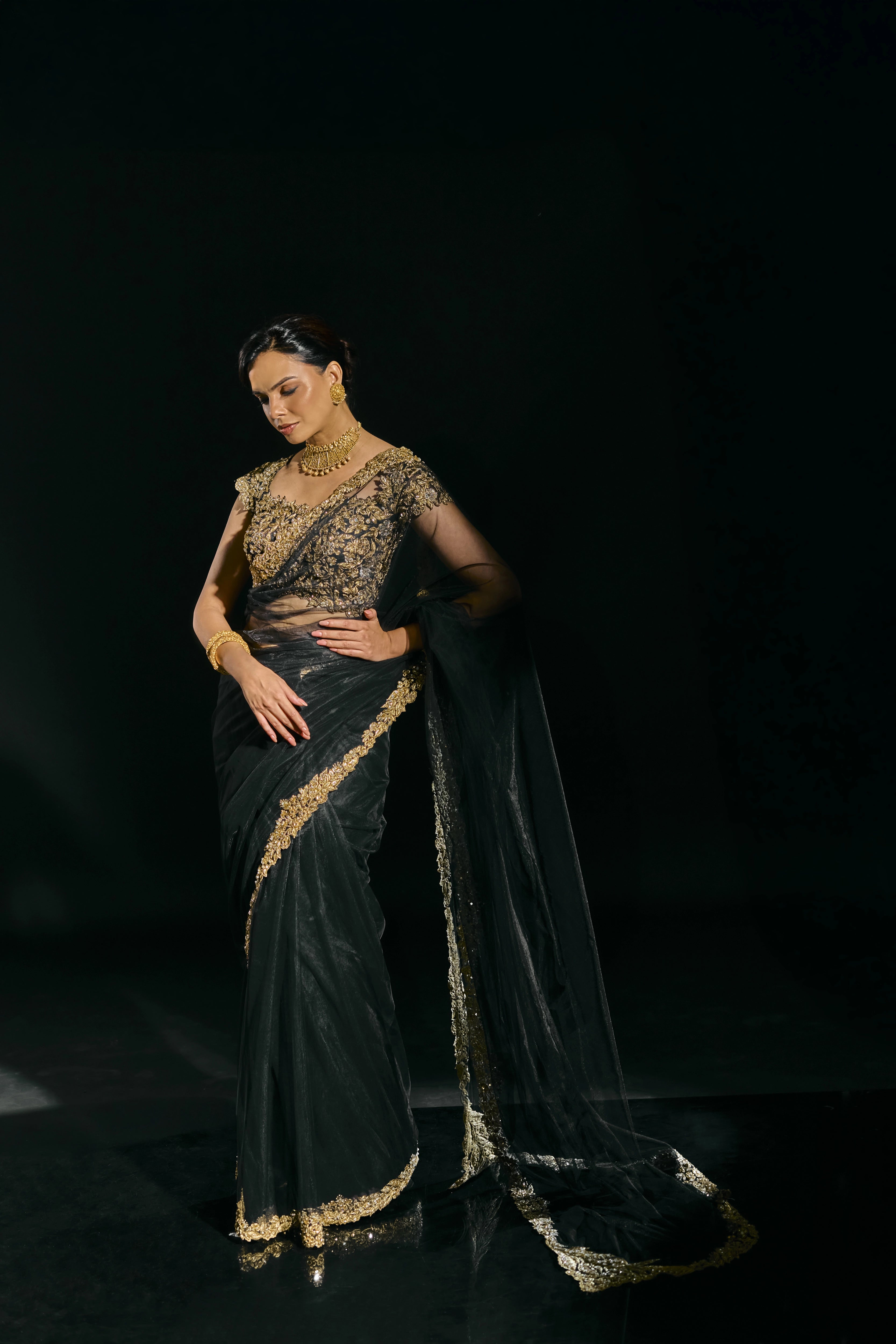 Model Jane C Thompson in a black net saree with a gold blouse, handcrafted with zari, zardosi, sequins, stones and crystals for "HAZE" - A/W'25 capsule collection by Archana Karthick.