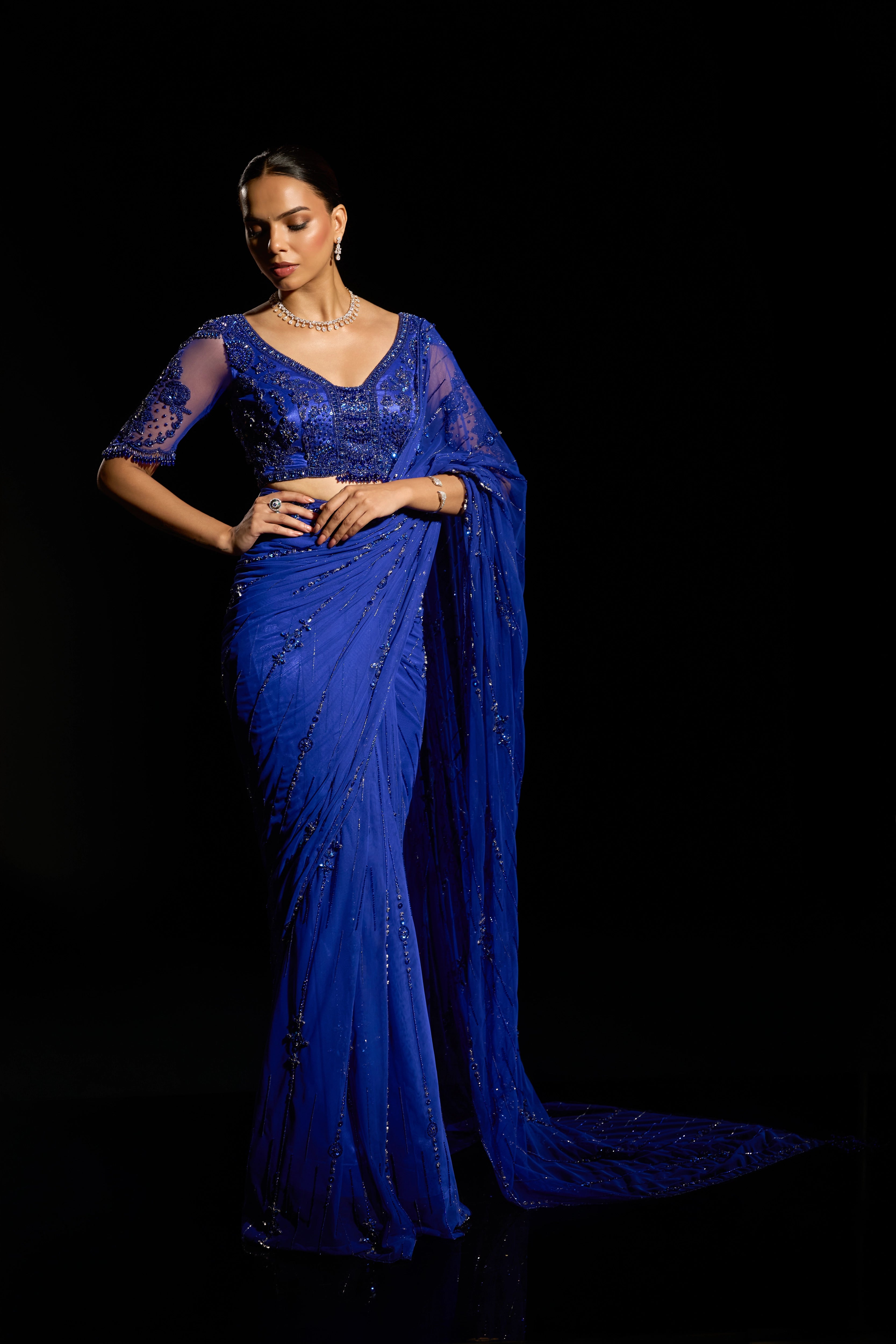 Model Jane C Thompson posing for a photoshoot in a sapphire blue saree set intricately adorned with sequins, rhinestones, crystals and cutdana for "STARDUST" - A/W'25 saree collection by team Archana Karthick.