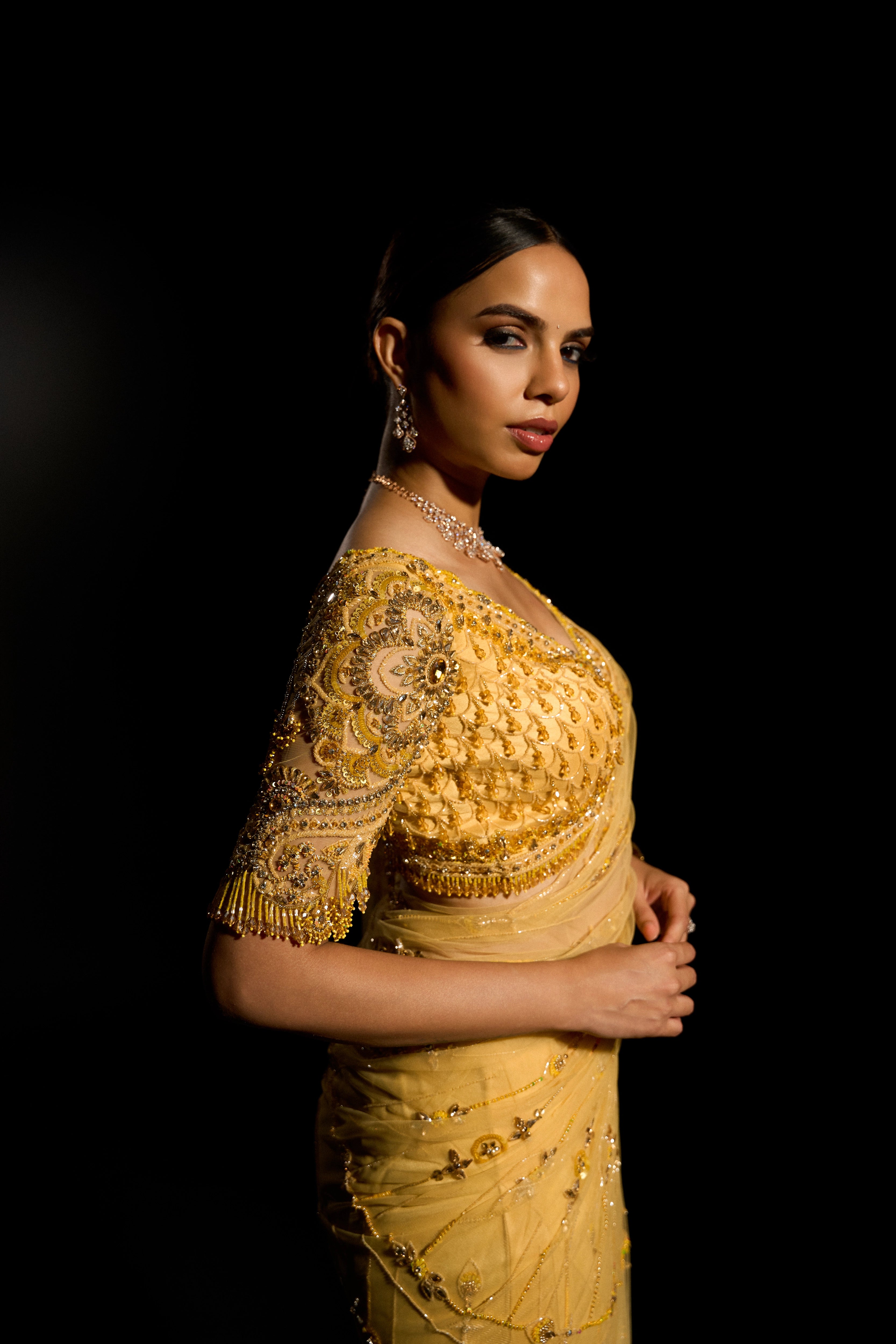Model Jane C Thompson posing for blouse sleeve in a yellow saree set intricately adorned with sequins, rhinestones, crystals and cutdana for "STARDUST" - A/W'25 saree collection by team Archana Karthick.