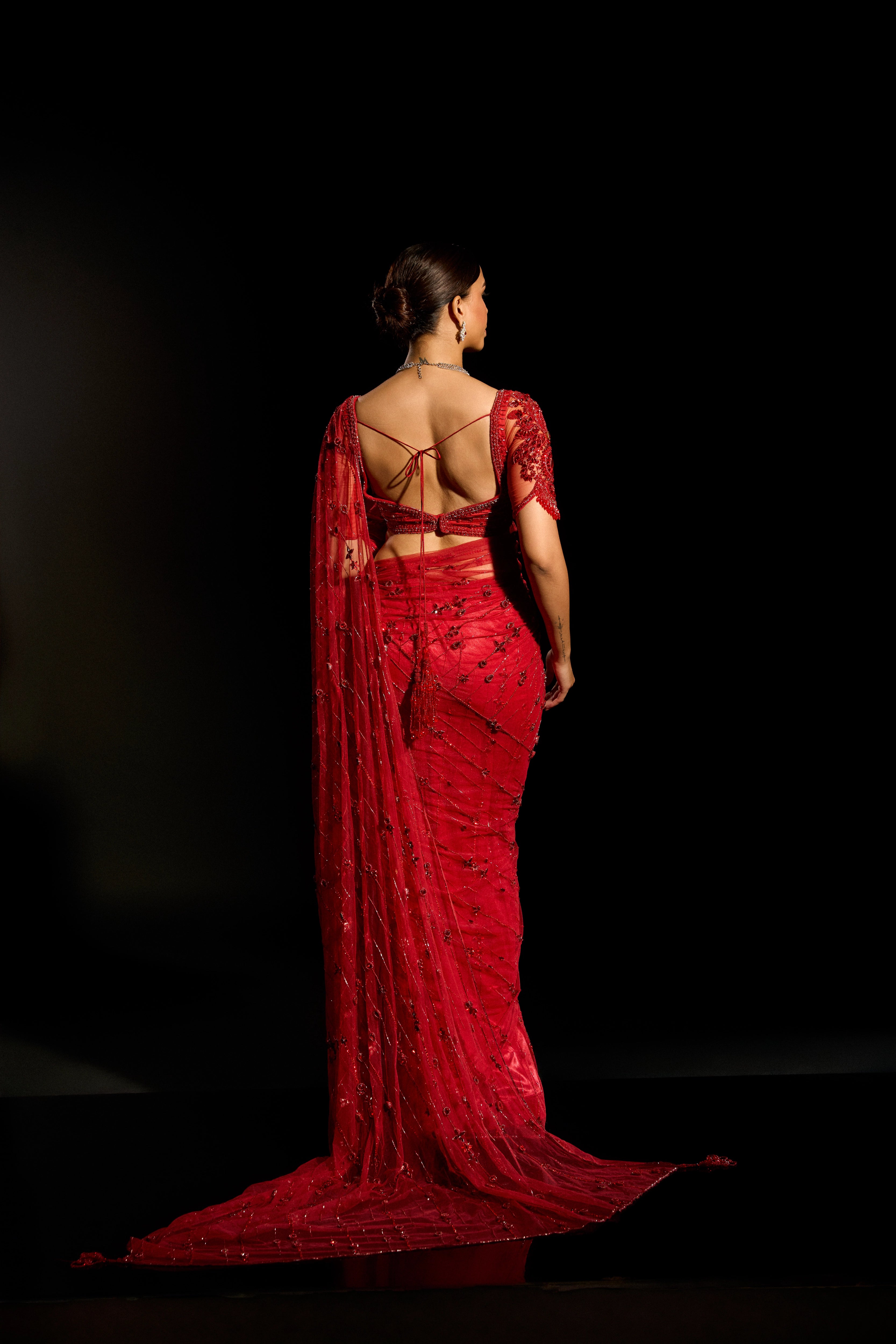 Model Jane C Thompson showcasing back blouse and saree design in a red saree set intricately adorned with sequins, rhinestones, crystals and cutdana for "STARDUST" - A/W'25 saree collection by team Archana Karthick.