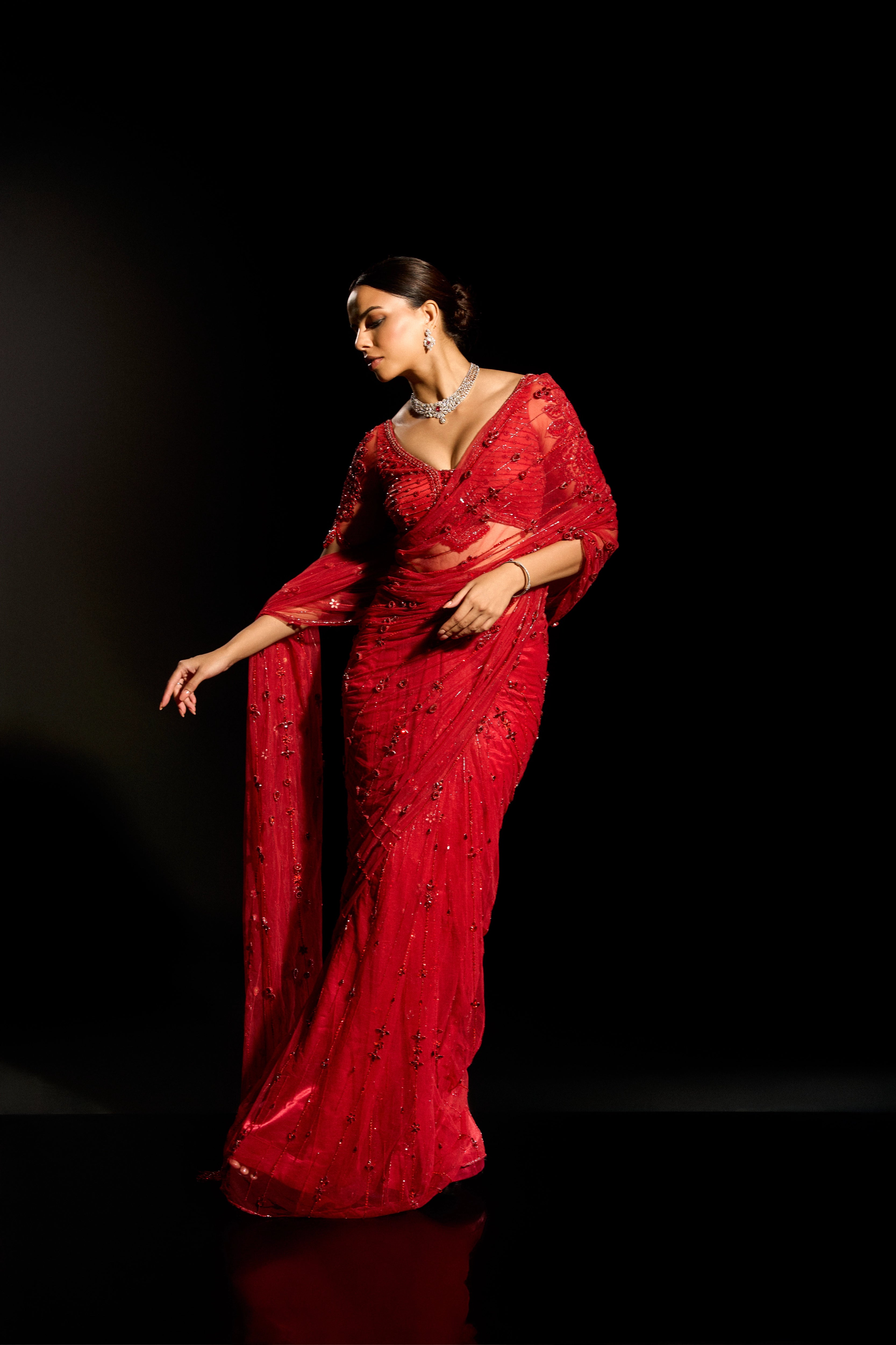 Model Jane C Thompson showcasing front profile in a red saree set intricately adorned with sequins, rhinestones, crystals and cutdana for "STARDUST" - A/W'25 saree collection by team Archana Karthick.