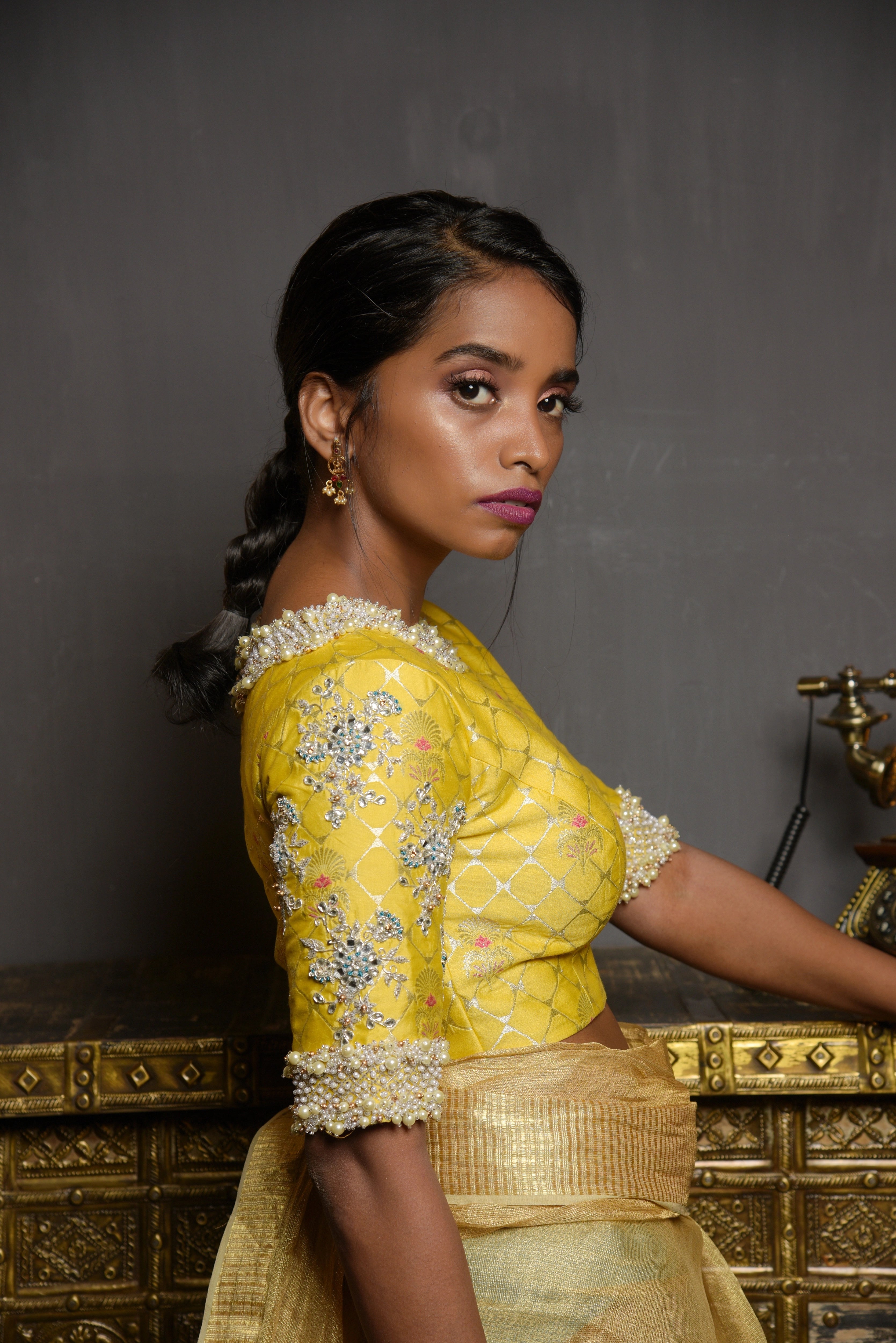 Model Pravallika Prasanna Raju posing for photoshoot in a yellow banarasi silk blouse with pearl embellishments on sleeves.