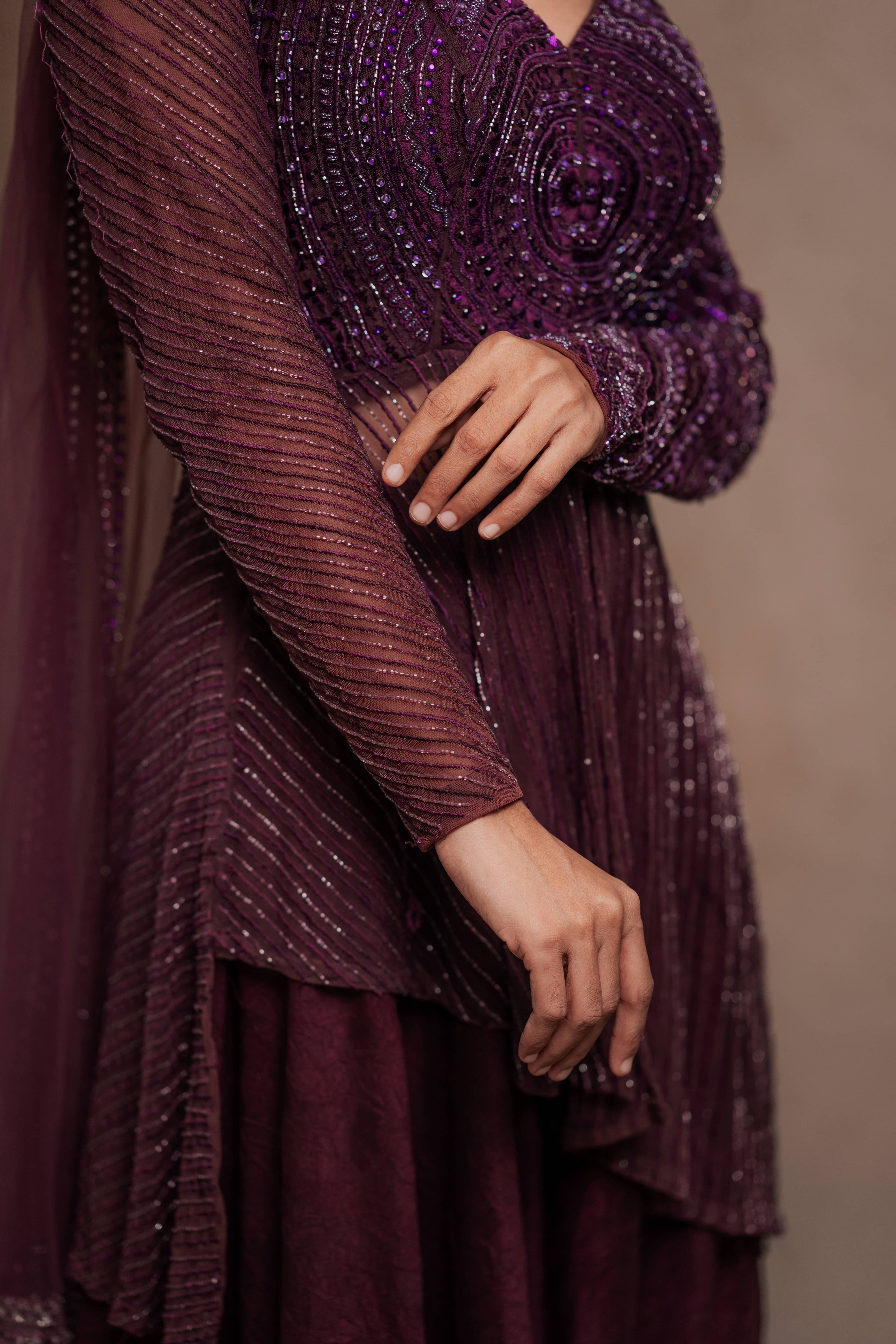 Model Premika Sekar in aubergine peplum sharara posing for closeup of sleeve design