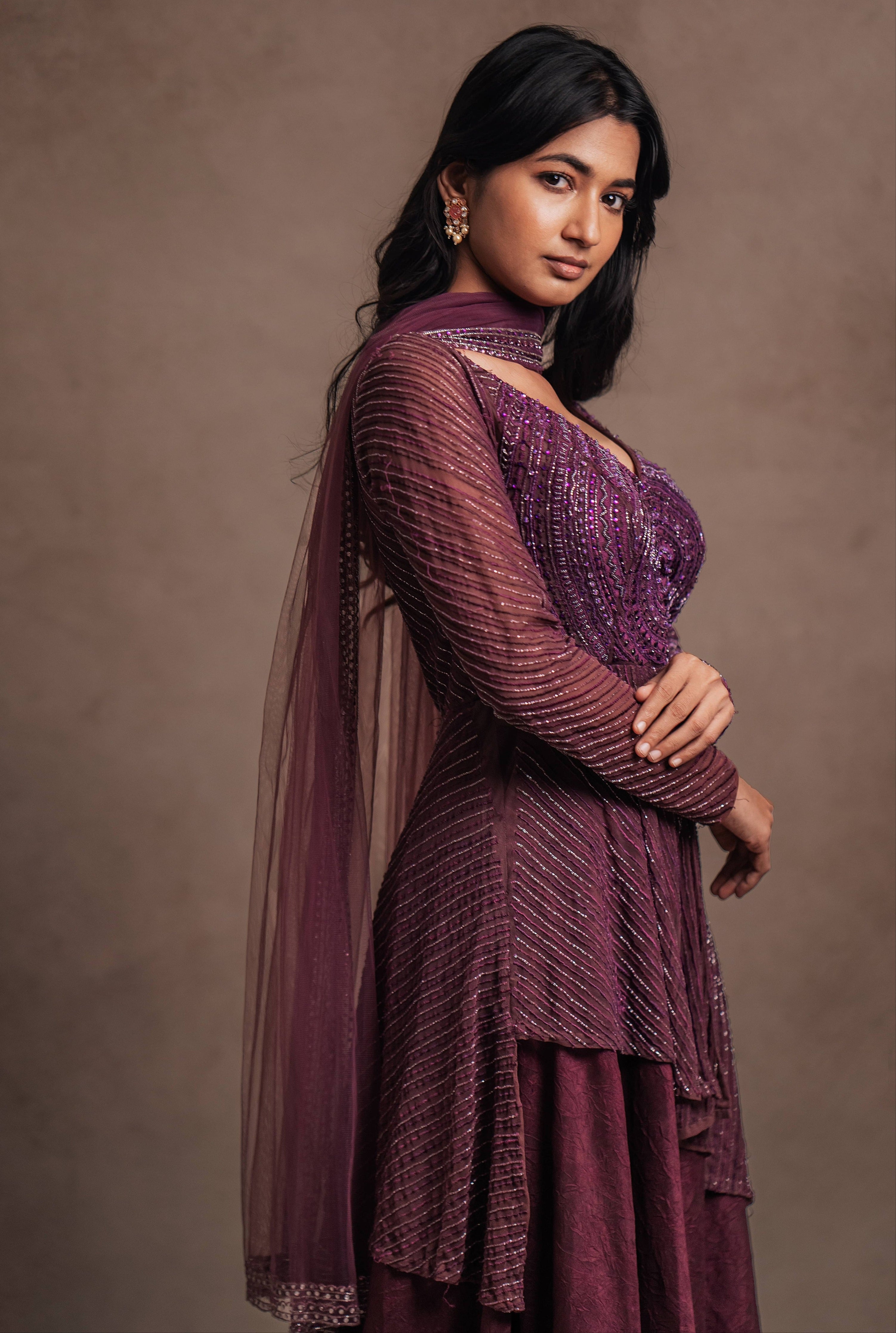 Model Premika Sekar in aubergine peplum sharara posing for side profile