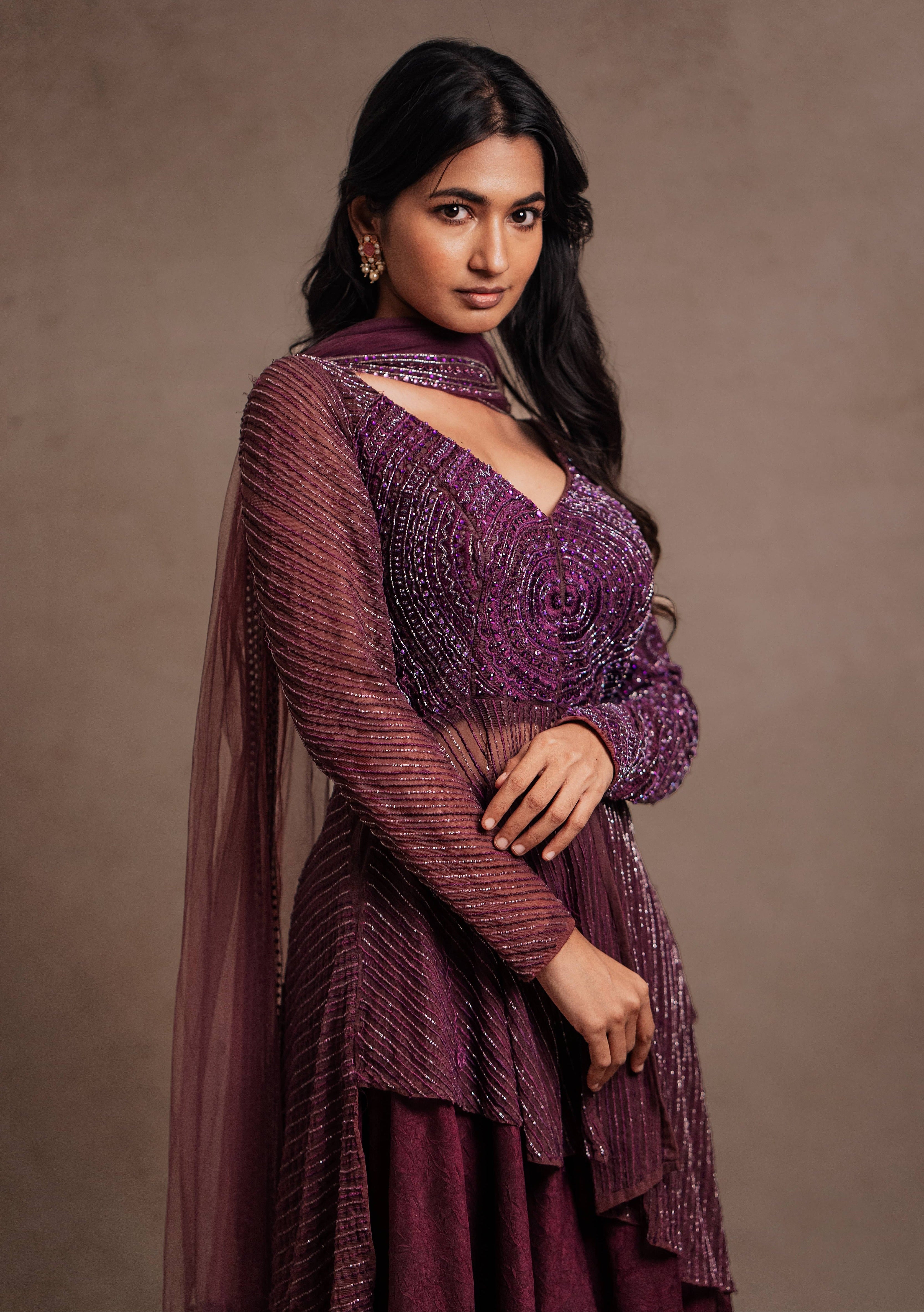 Model Premika Sekar in aubergine peplum sharara posing looking at lens