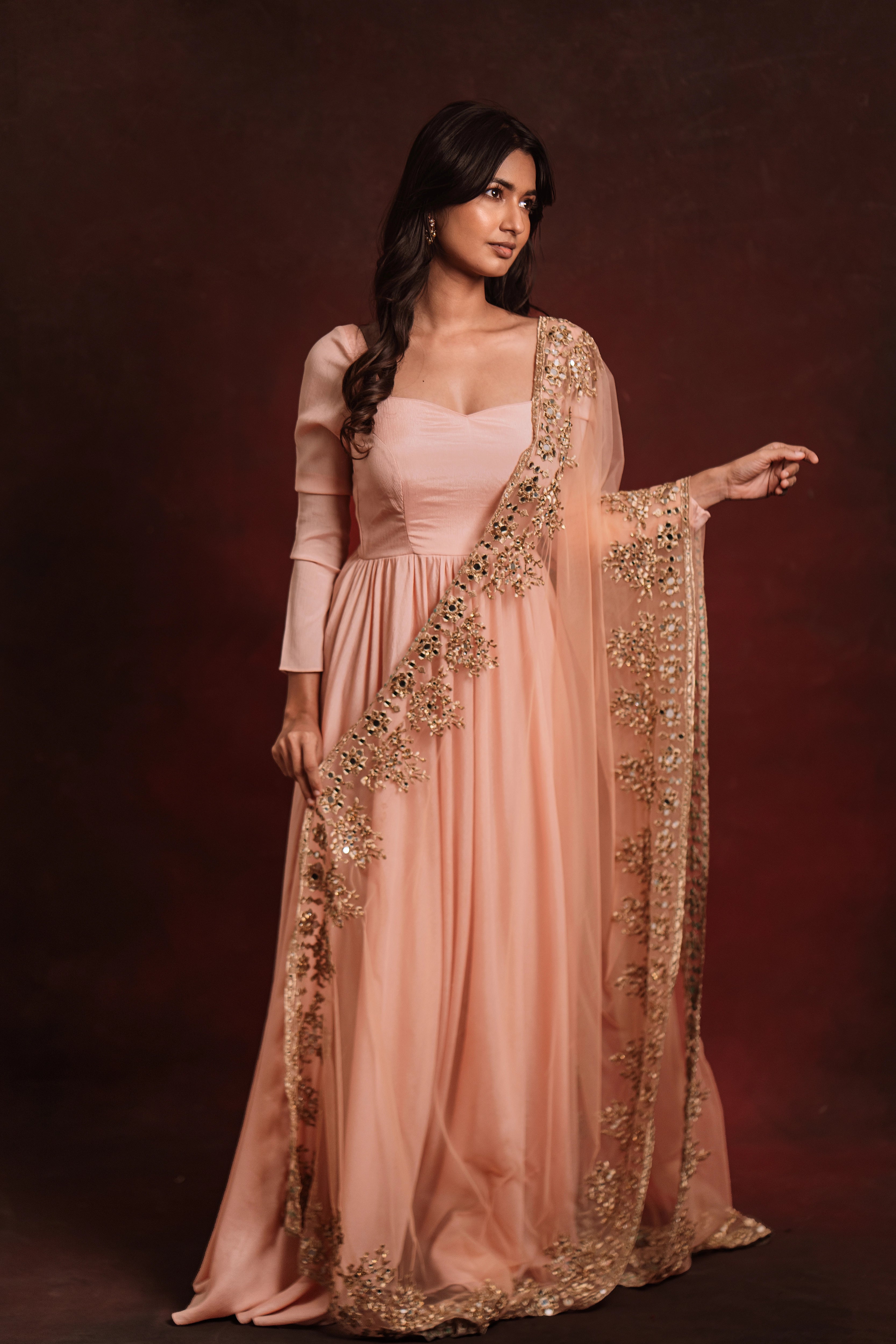 Model in "Mellow Peach", a georgette anarkali paired with a handcrafted tulle dupatta, for a festive look, while keeping the trend intact.
