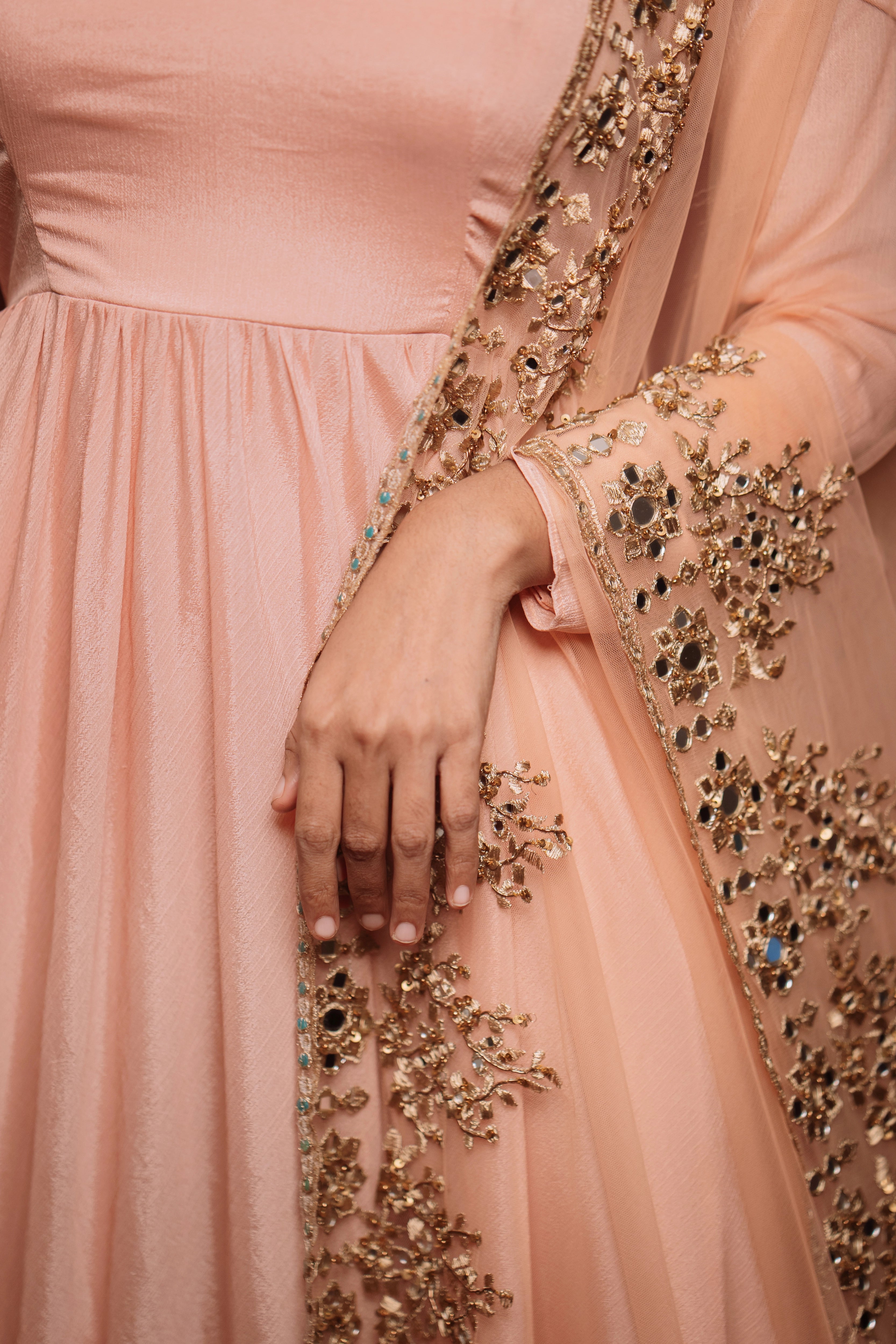Model showcasing detailings in "Mellow Peach", a georgette anarkali paired with a handcrafted tulle dupatta, for a festive look, while keeping the trend intact.