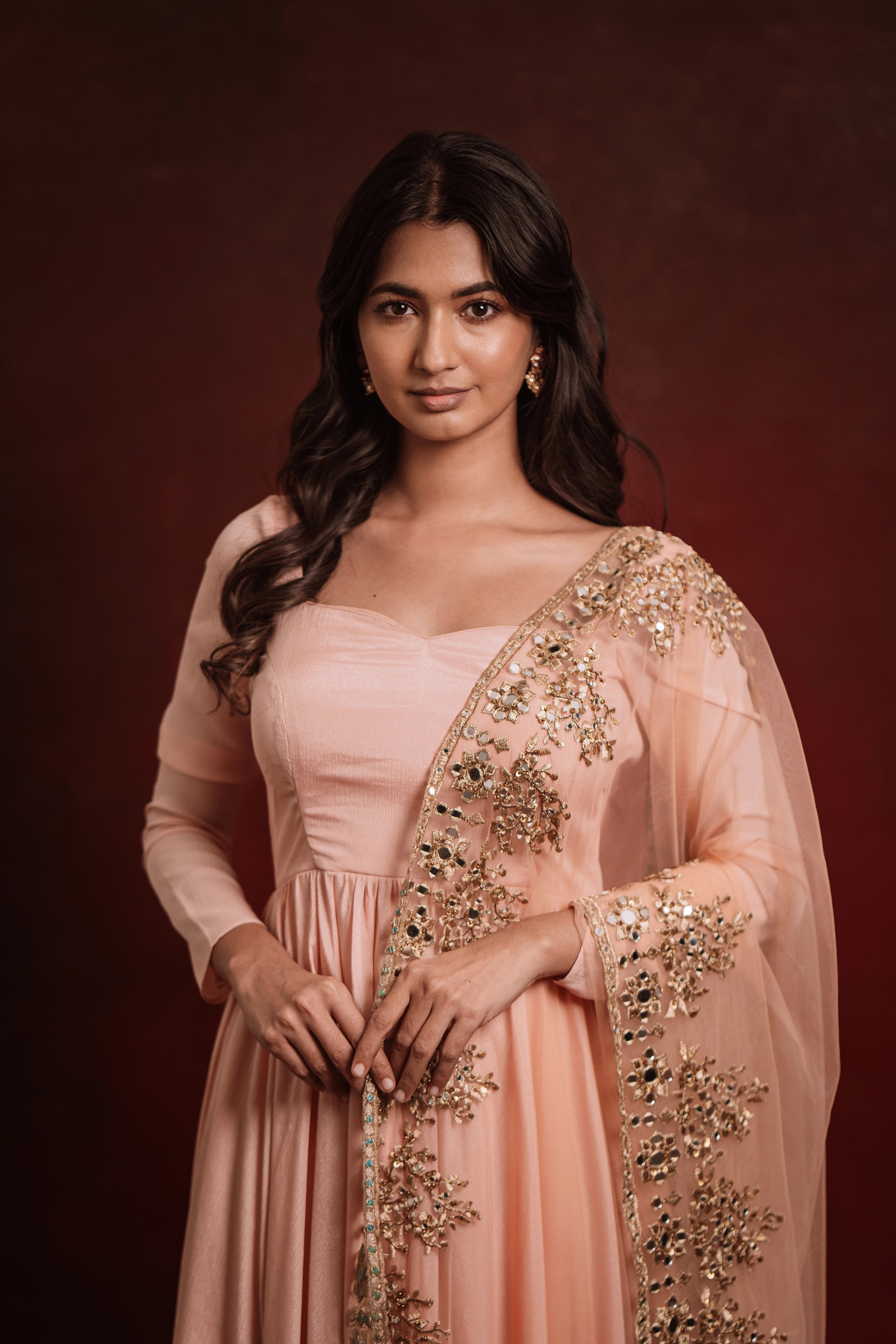 Model smiling at lens in "Mellow Peach", a georgette anarkali paired with a handcrafted tulle dupatta, for a festive look, while keeping the trend intact.