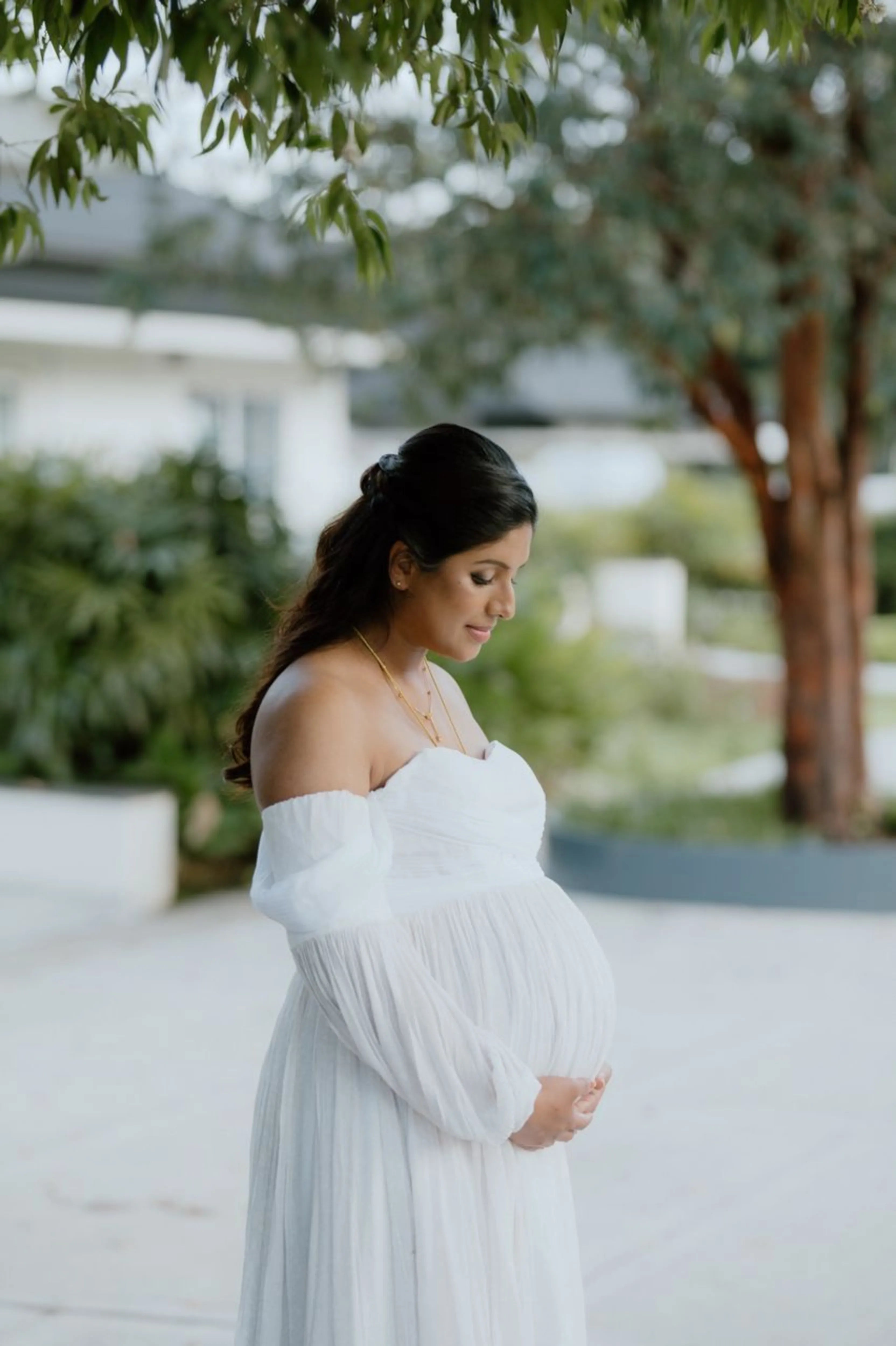 Mom to be Anusha Rajendran from Singapore smiling in a white georgette corset maternity gown by Archana Karthick.