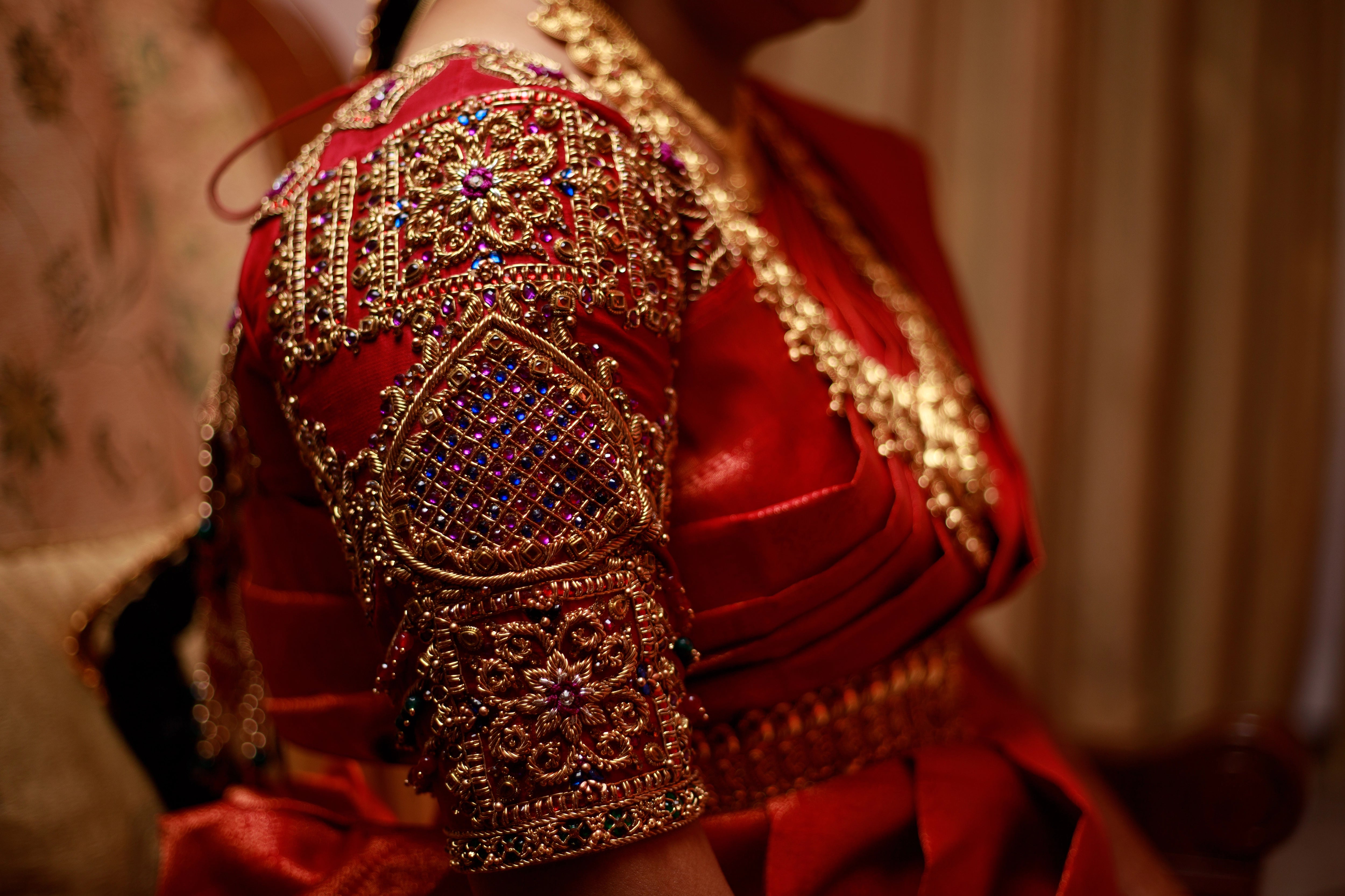 Mom to be Gayathri Kiran Kumar showcasing sleeve in a red silk blouse for her baby shower / seemantham, intricately handcrafted with kemp stones, zardozi and beads by team Archana Karthick.