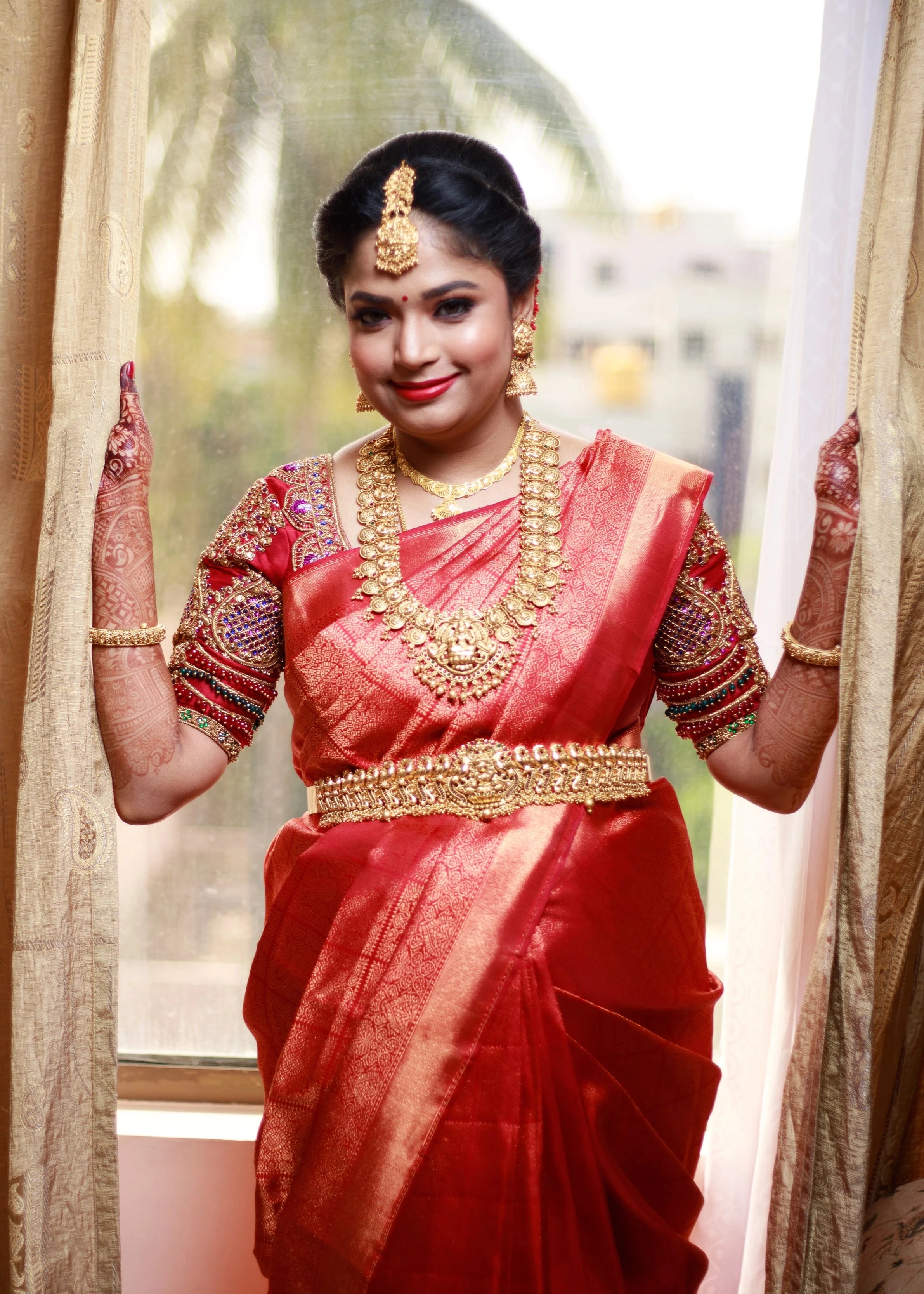 Mom to be Gayathri Kiran Kumar smiling in a red silk blouse for her baby shower / seemantham, intricately handcrafted with kemp stones, zardozi and beads by team Archana Karthick.