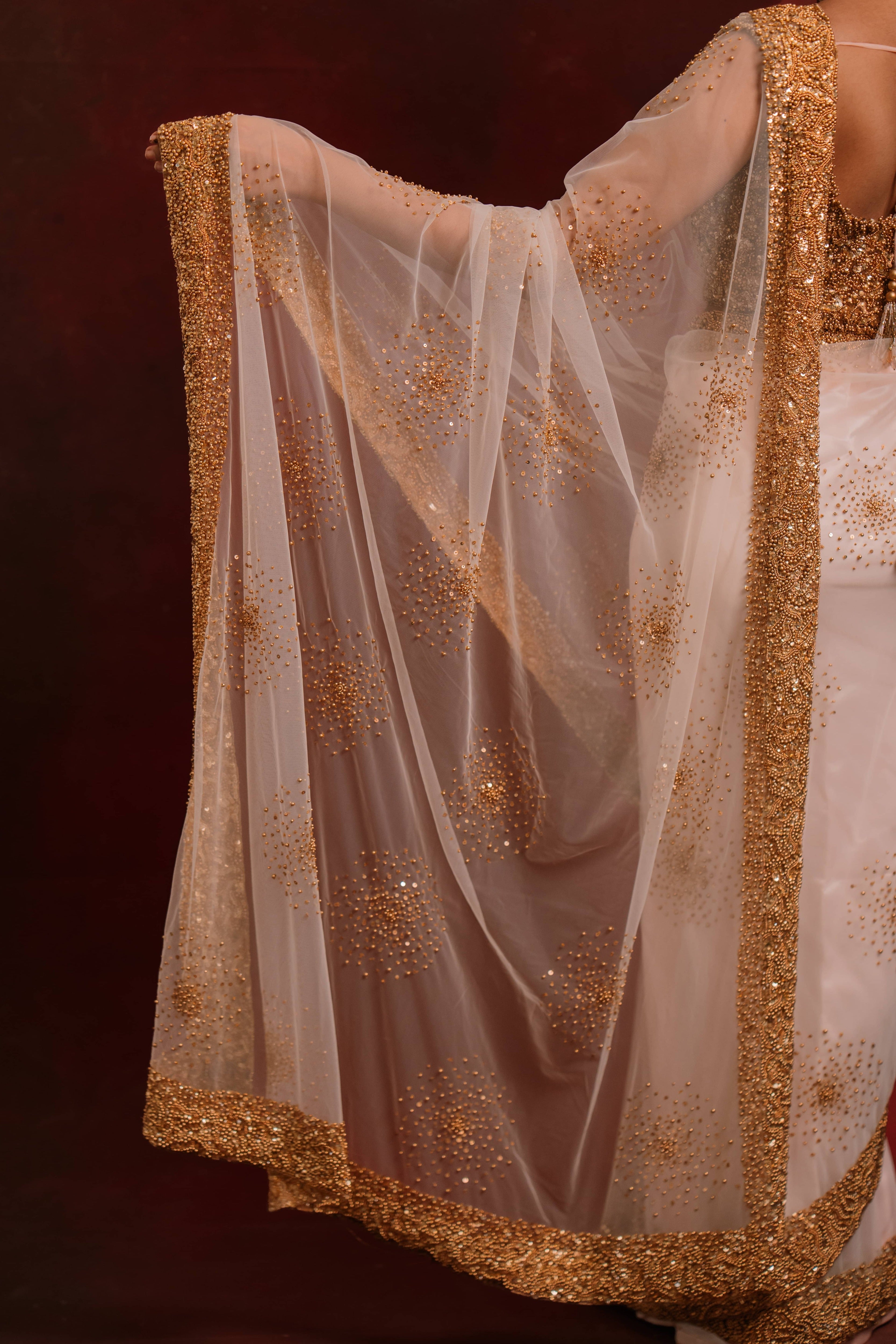Pallu design details of ivory tulle saree intricately handcrafted with antique gold beads and sequins paired with a handcrafted blouse featuring similar work by team Archana Karthick