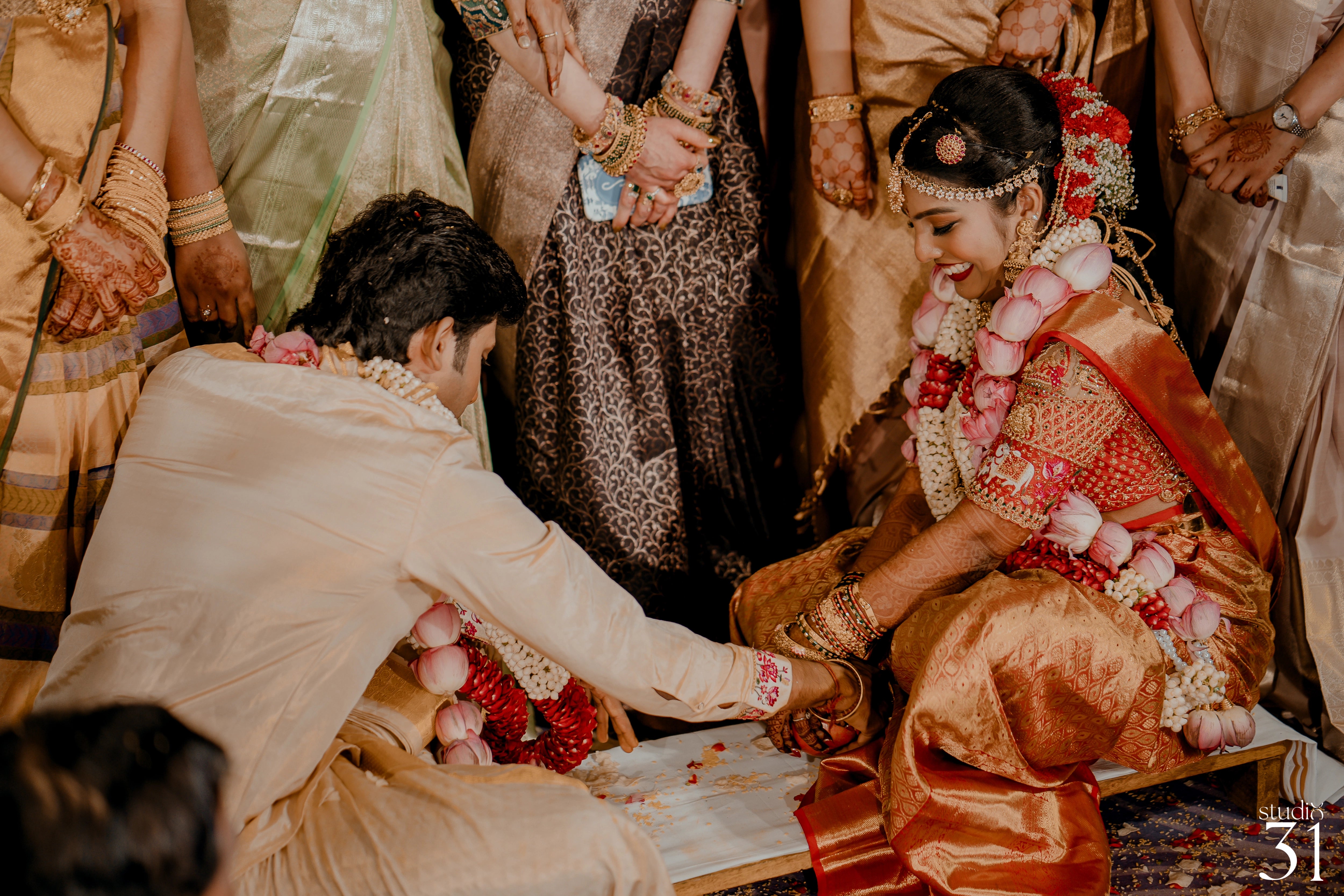 Pooja & Rhevanth during rituals for their wedding in red silk blouse and white silk veshti and shirt - intricately handcrafted by team Archana Karthick.